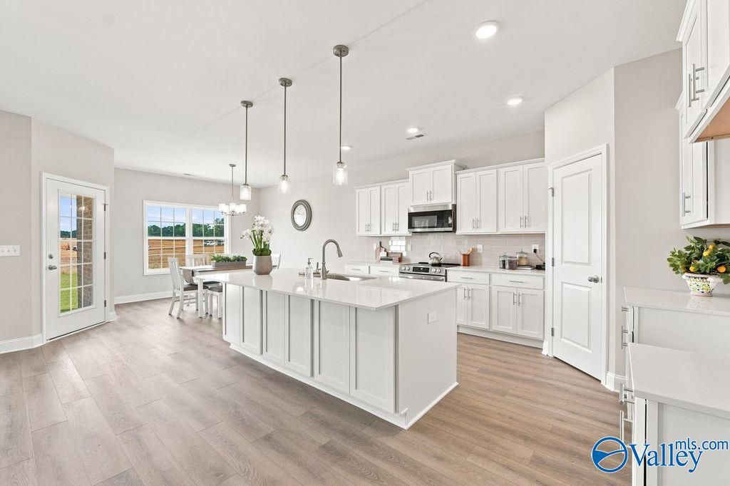 Bright white kitchen with large center island, pendant lights, and hardwood floors in Davidson Homes' Harrison floor plan, Hartselle, AL