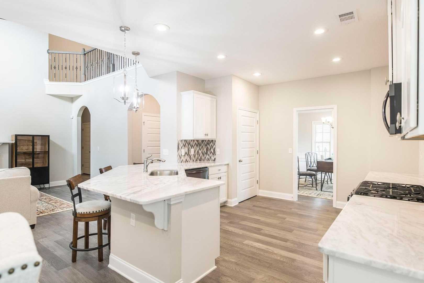Spacious open-concept kitchen and living room at Links Crossing in Auburn AL with white cabinets, marble island, and fireplace
