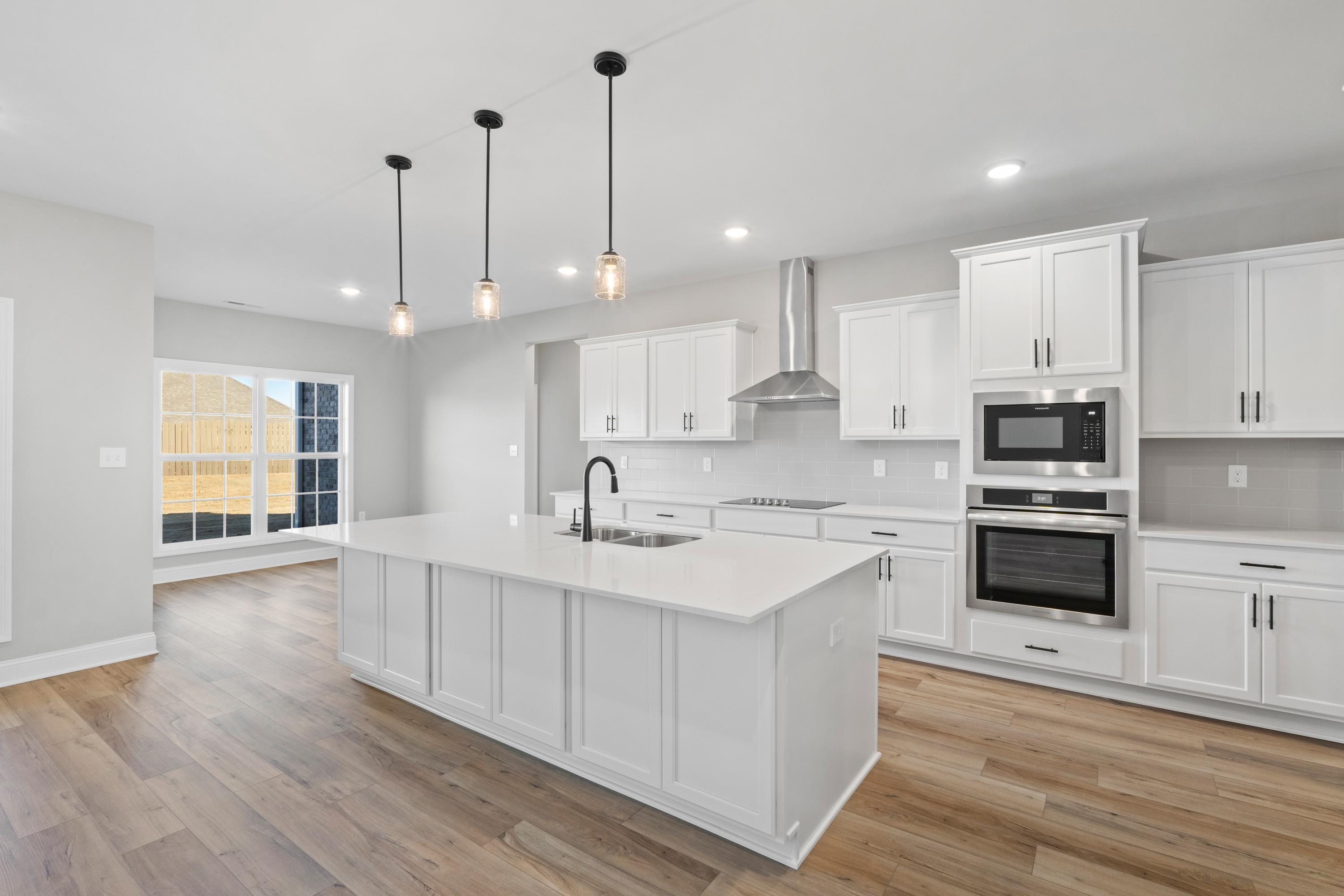 Modern Valencia kitchen by Davidson Homes featuring white island sink, double ovens, pendant lights, and hardwood floors