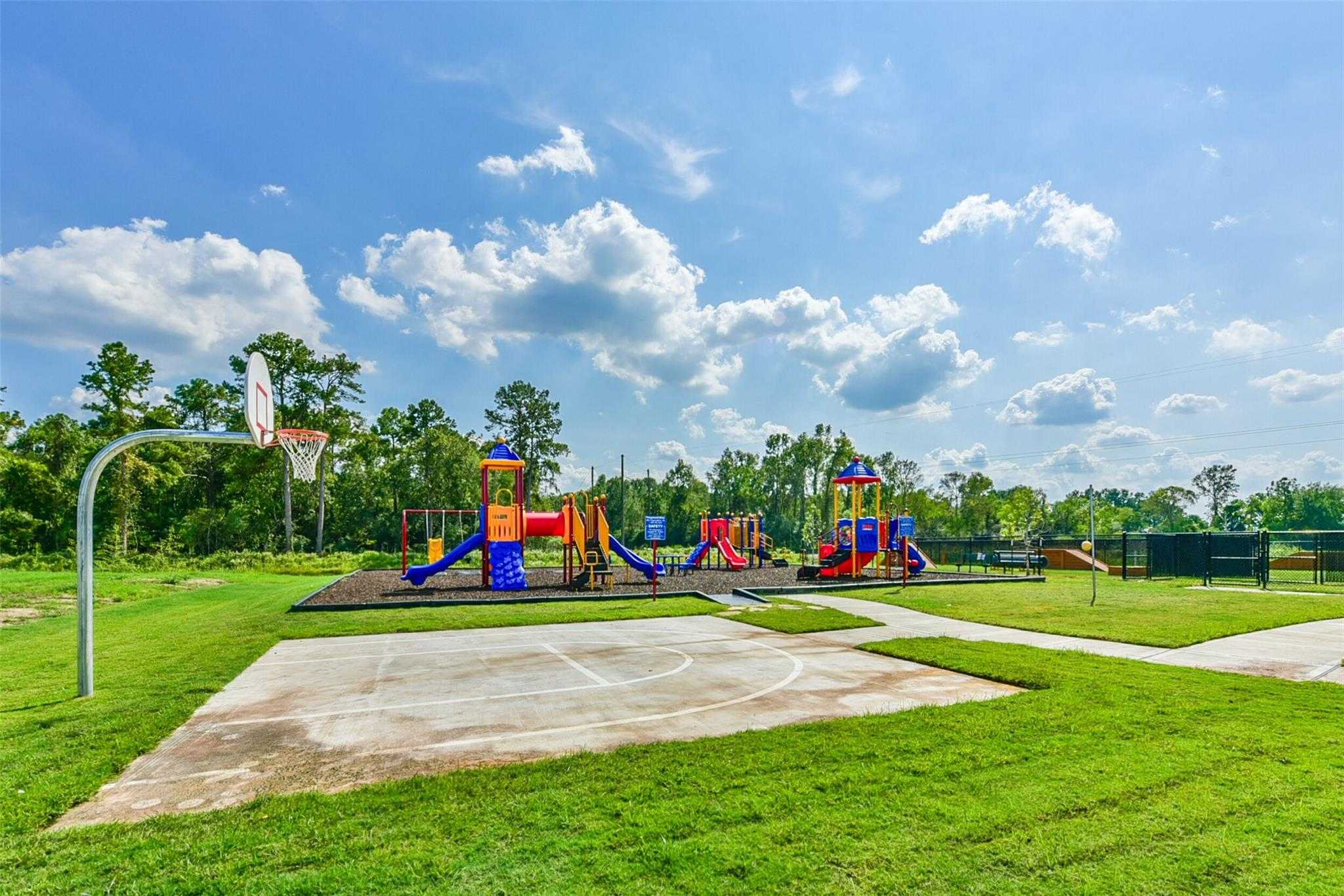 Vibrant playground with colorful slides, swings and climbing structures beside basketball court in The Villages at WestPointe, Dayton, Texas