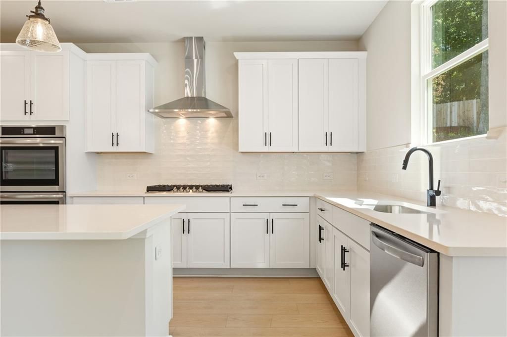 Modern white kitchen with large island, stainless steel appliances, subway tile backsplash in Davidson Homes The Hickory E, Buford, GA