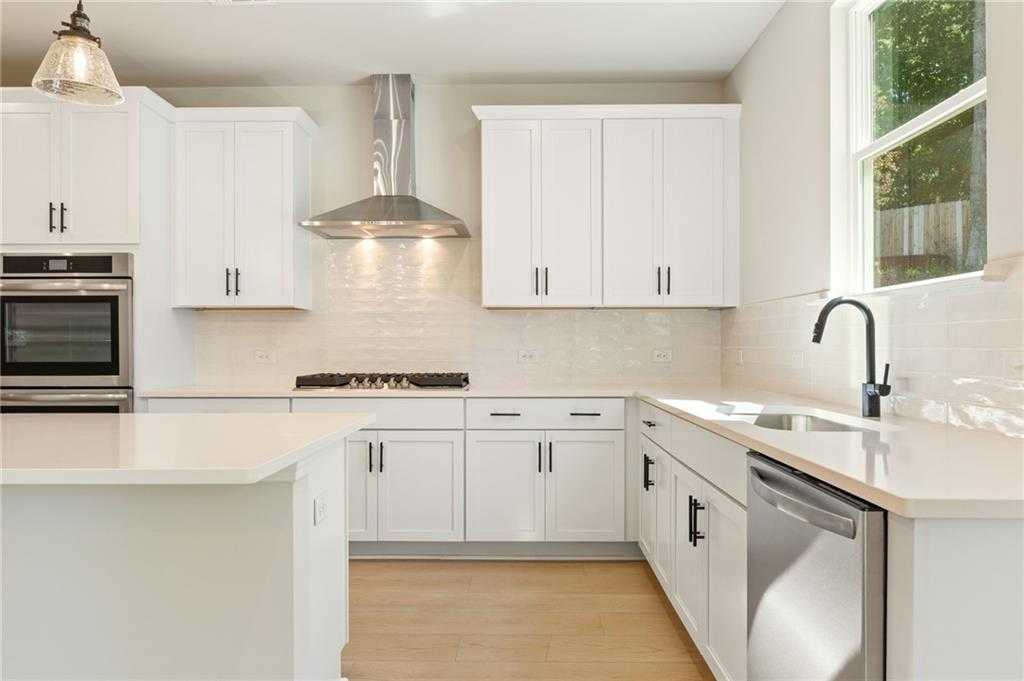 Modern white kitchen with stainless appliances, subway tile backsplash, and large island in Davidson Homes The Hickory E, Buford, GA