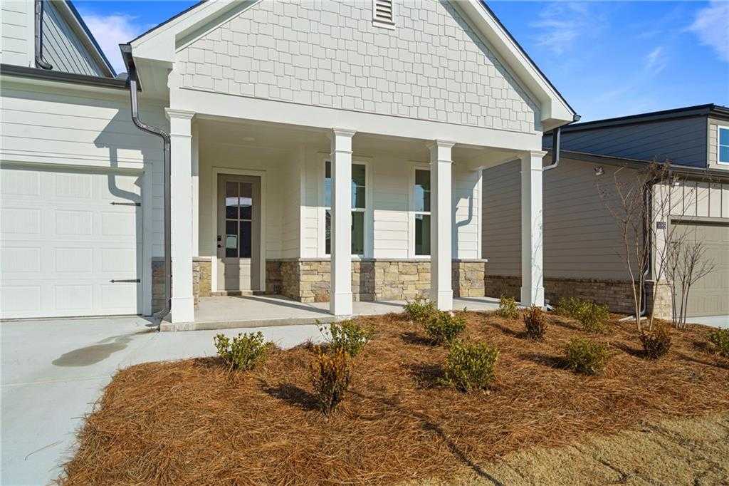 The Edison A front exterior: white shiplap siding, columned porch, 2-car garage, stone accents, landscaped yard in Kelly Preserve, Loganville
