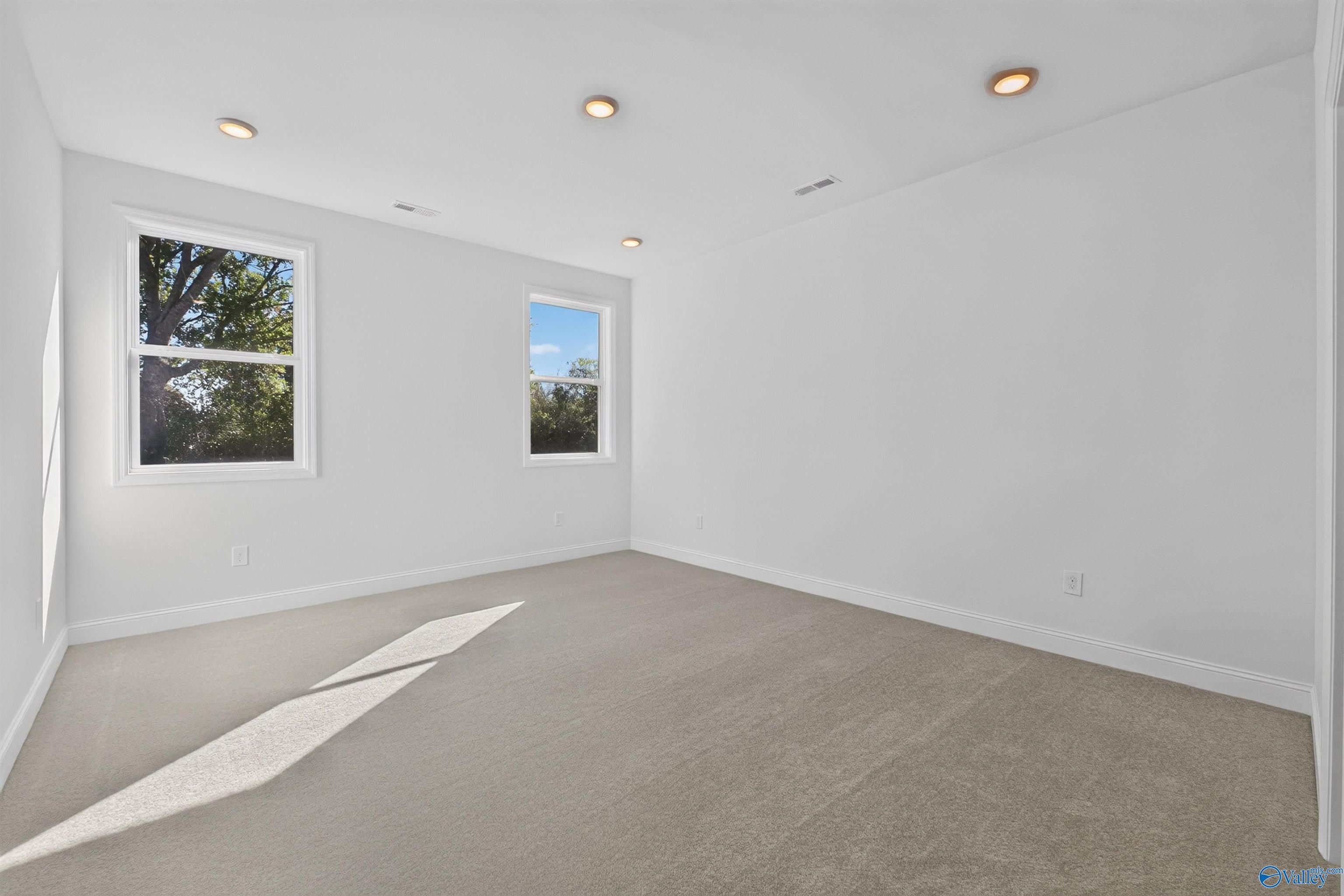 Bright empty bedroom with carpet, two windows, and recessed lighting in Davidson Homes Ashport L plan, New Market, Alabama