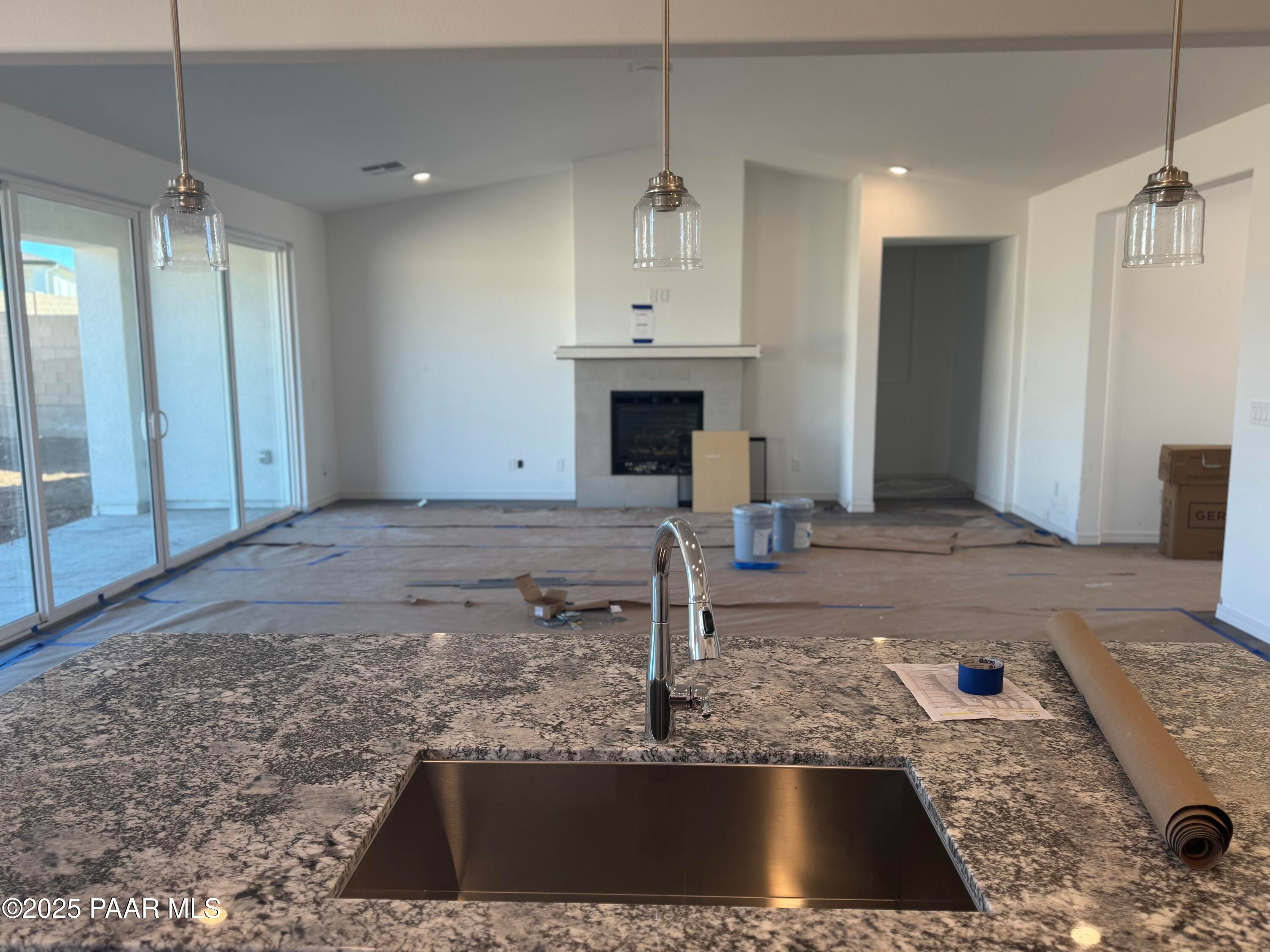 Modern open-concept kitchen with granite island, stainless sink, and pendant lights in Davidson Homes The Summit A, Prescott, Arizona