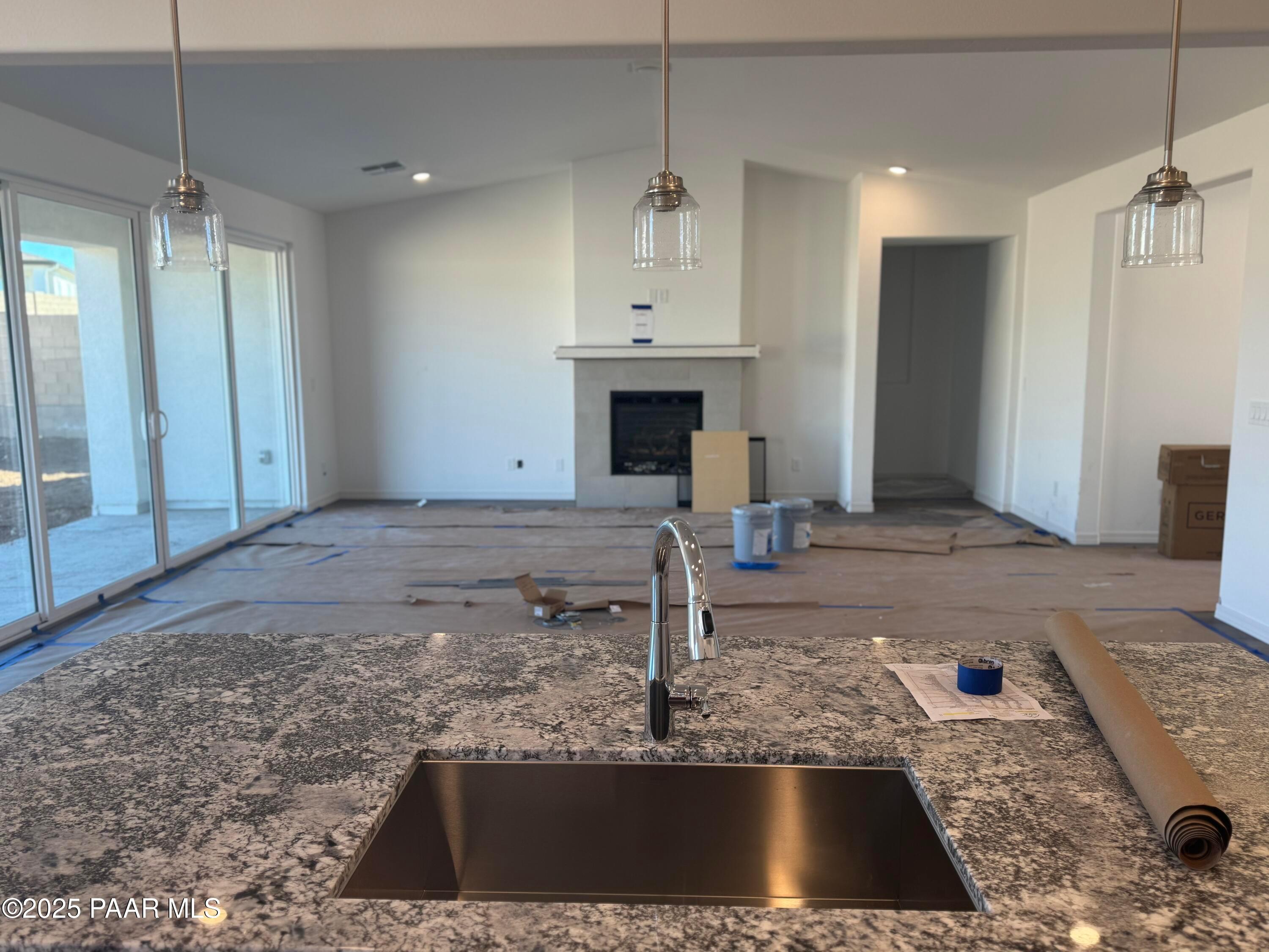Modern open-concept kitchen with granite island, stainless sink, and pendant lights in Davidson Homes The Summit A, Prescott, Arizona