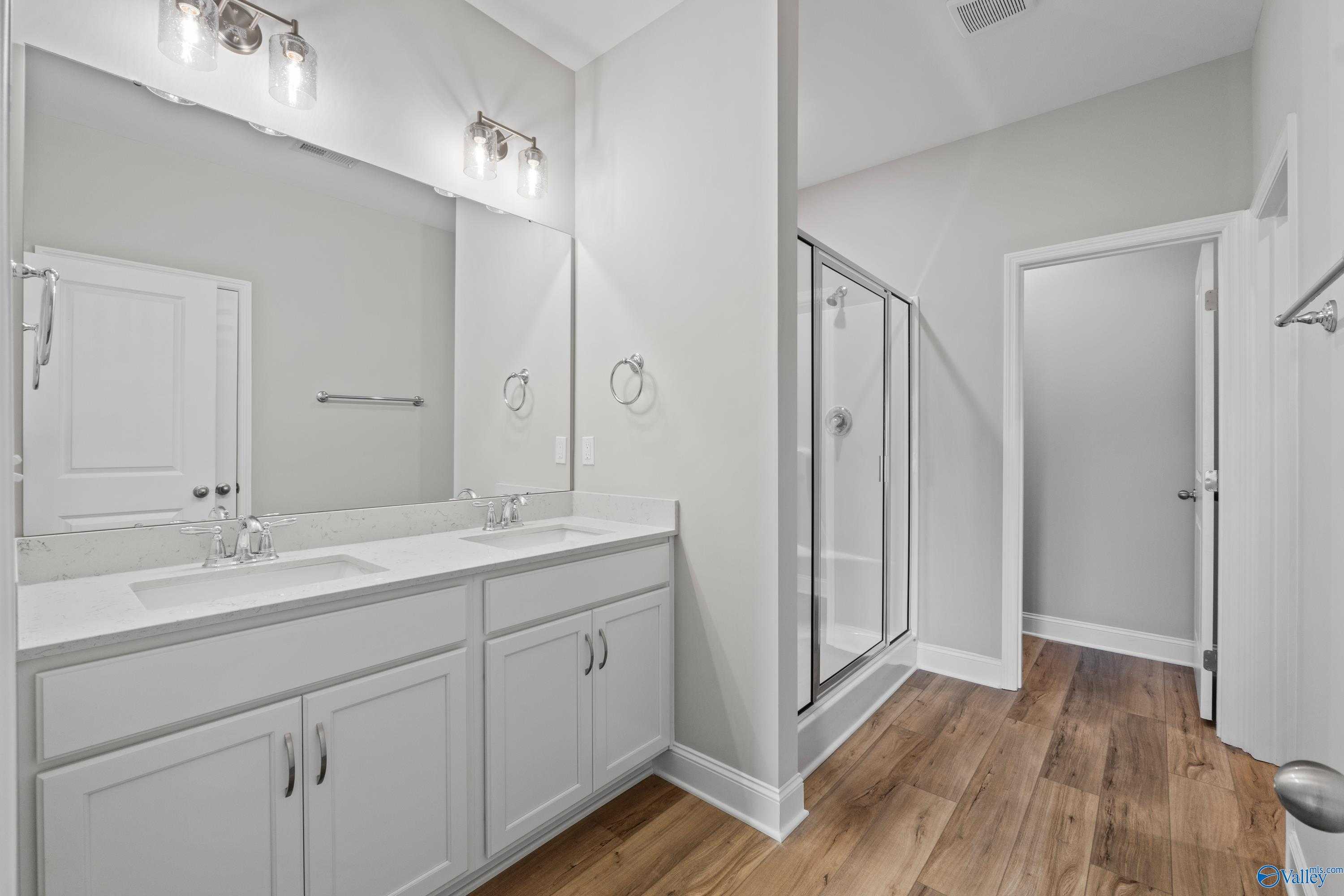 Modern master bathroom with dual sinks, large mirrors, frameless shower in Davidson Homes The Daphne C, Athens, AL