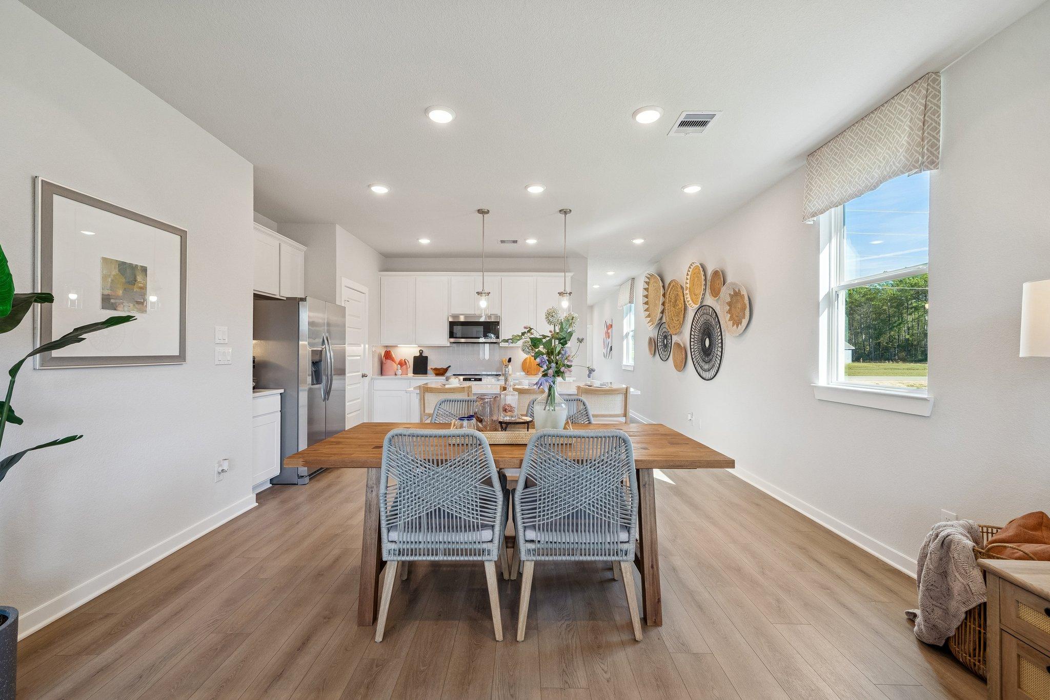 Open-concept kitchen dining area at Spring Branch Crossing in Conroe TX with white cabinets hardwood floors and woven wall decor