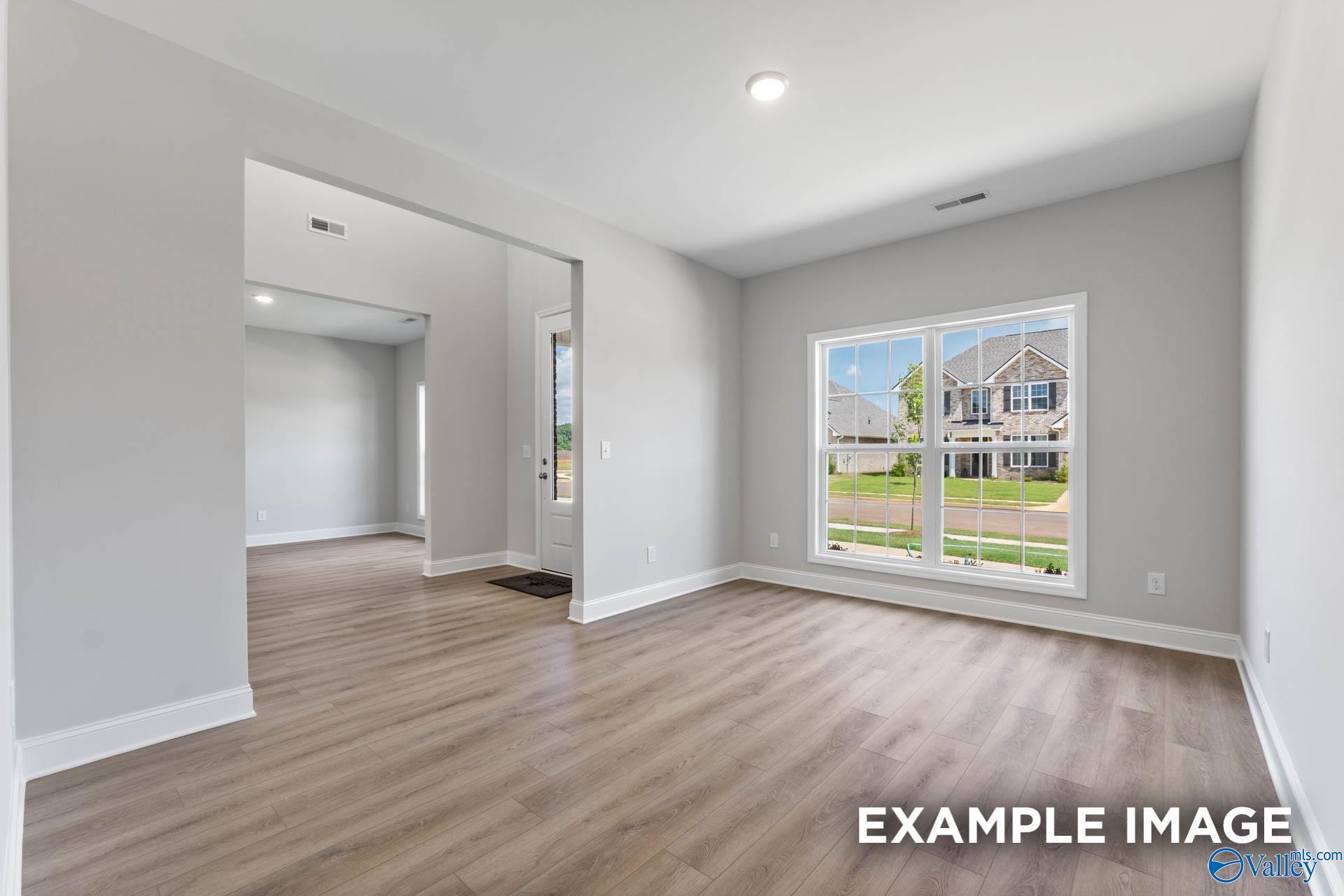 Bright open living room with luxury vinyl plank floors and large windows overlooking backyard in Davidson Homes The Madison A, Meridianville, Alabama