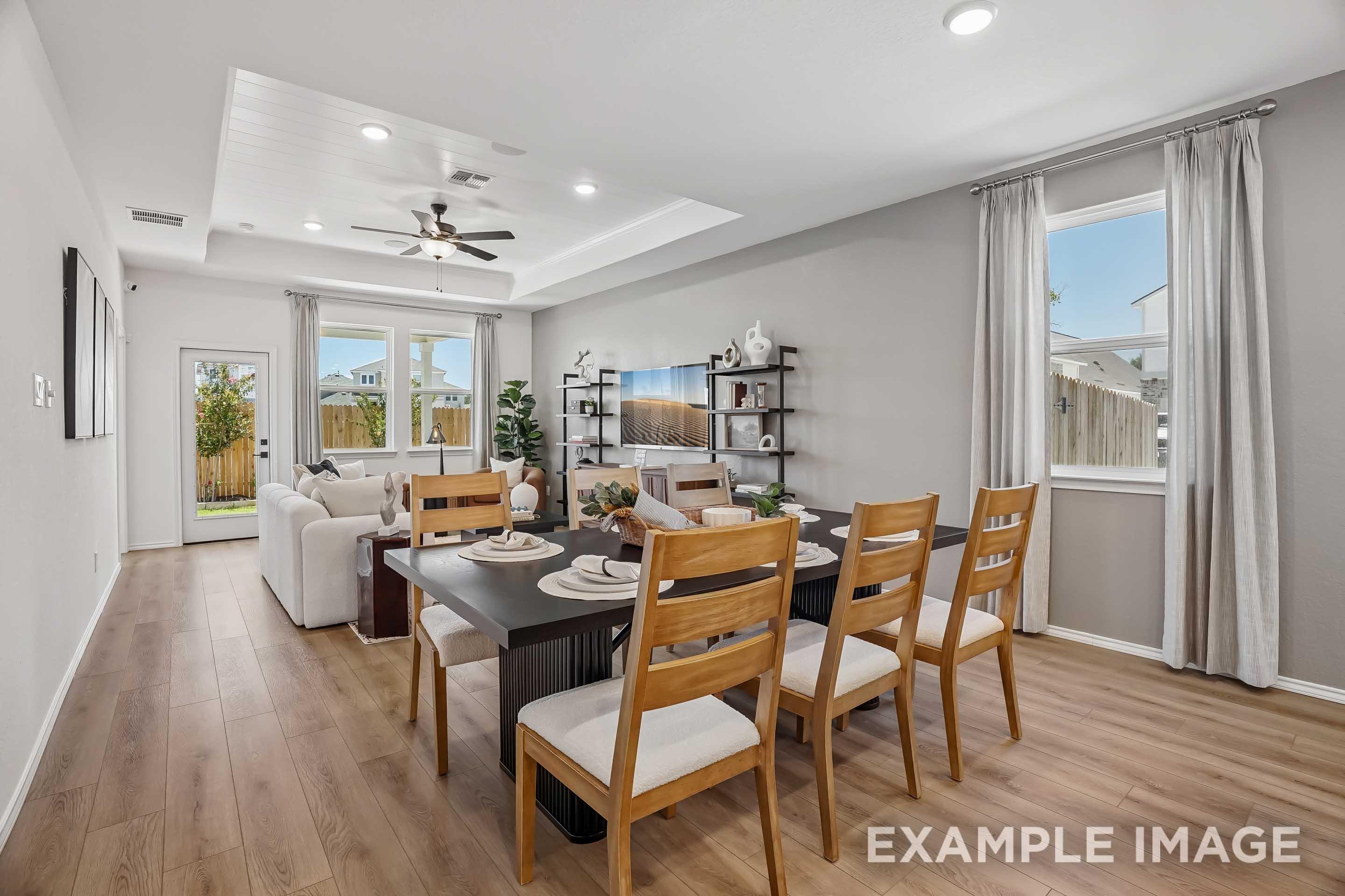 Open-concept dining and living area in The Pinecrest D model featuring tray ceilings and modern interior design.