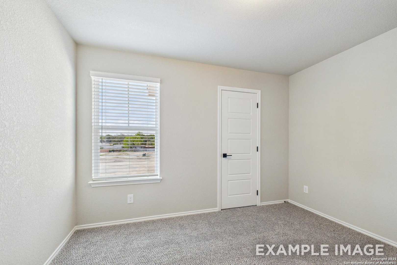 Bright secondary bedroom with beige walls, window blinds, and carpet in Davidson Homes The Charlotte A, San Antonio, Texas