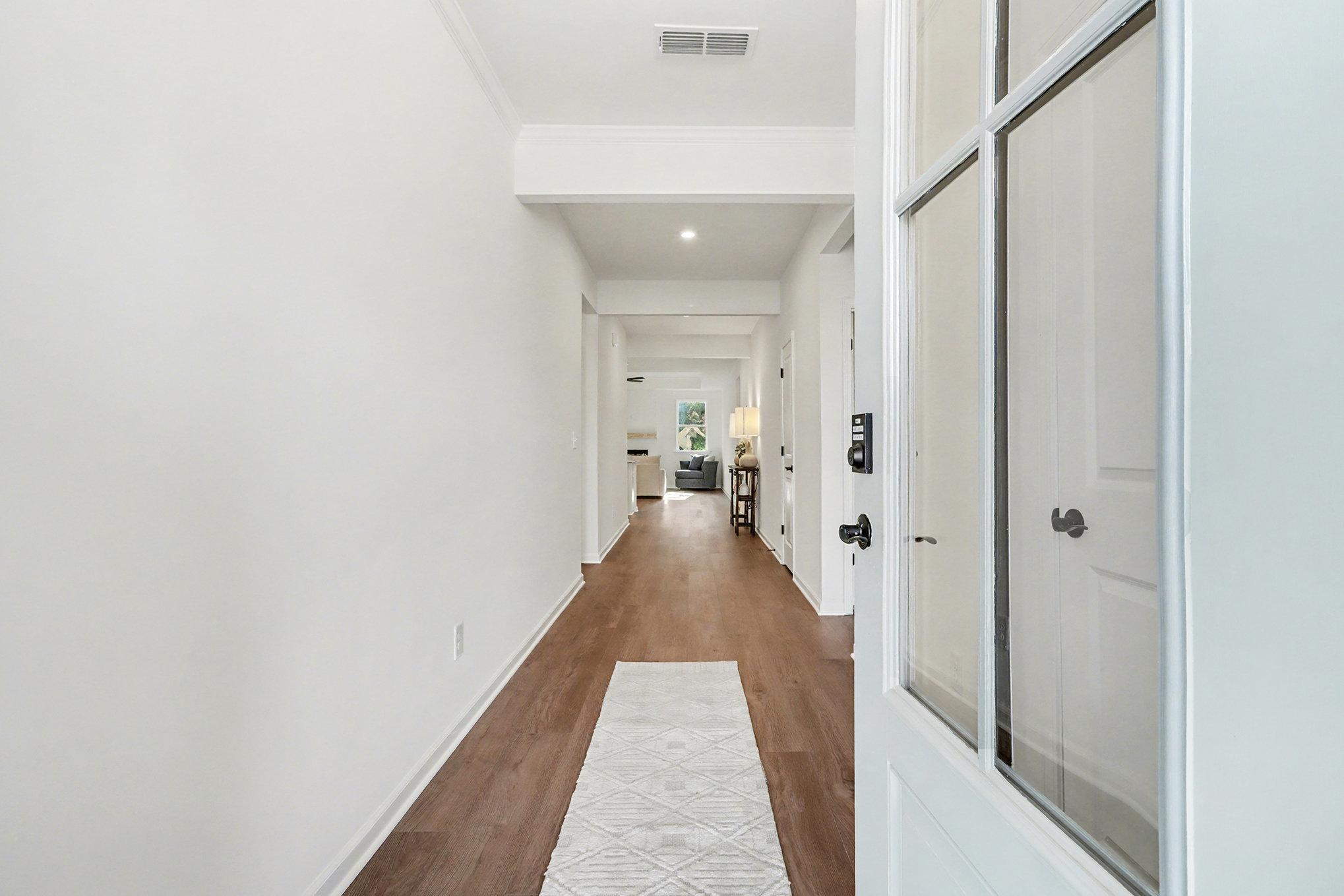 Welcoming entry foyer with hardwood floors, white doors, and glass-front entry in The Daphne B, Kelly Preserve, Loganville, GA