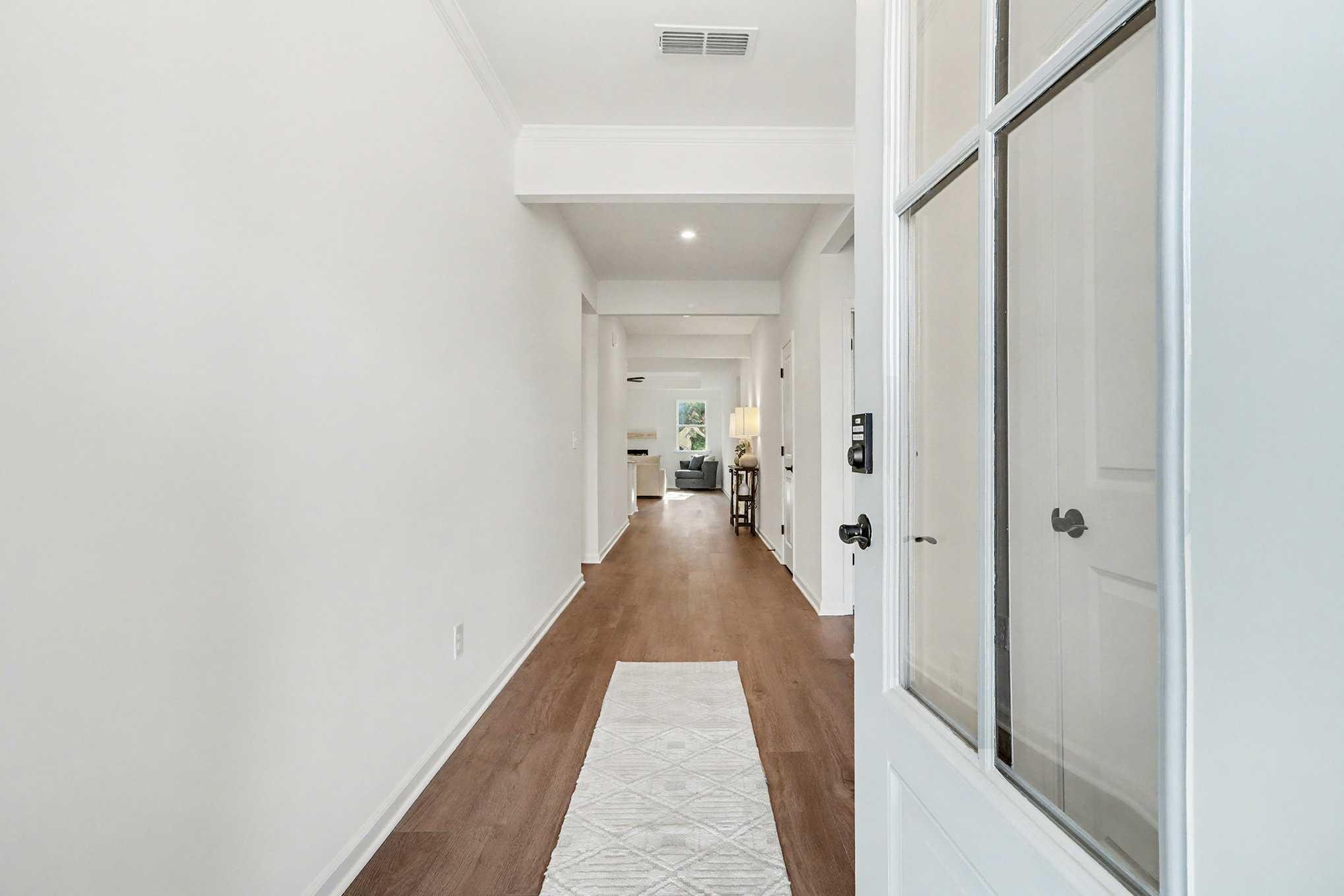 Welcoming entry foyer with hardwood floors, white doors, and glass-front entry in The Daphne B, Kelly Preserve, Loganville, GA