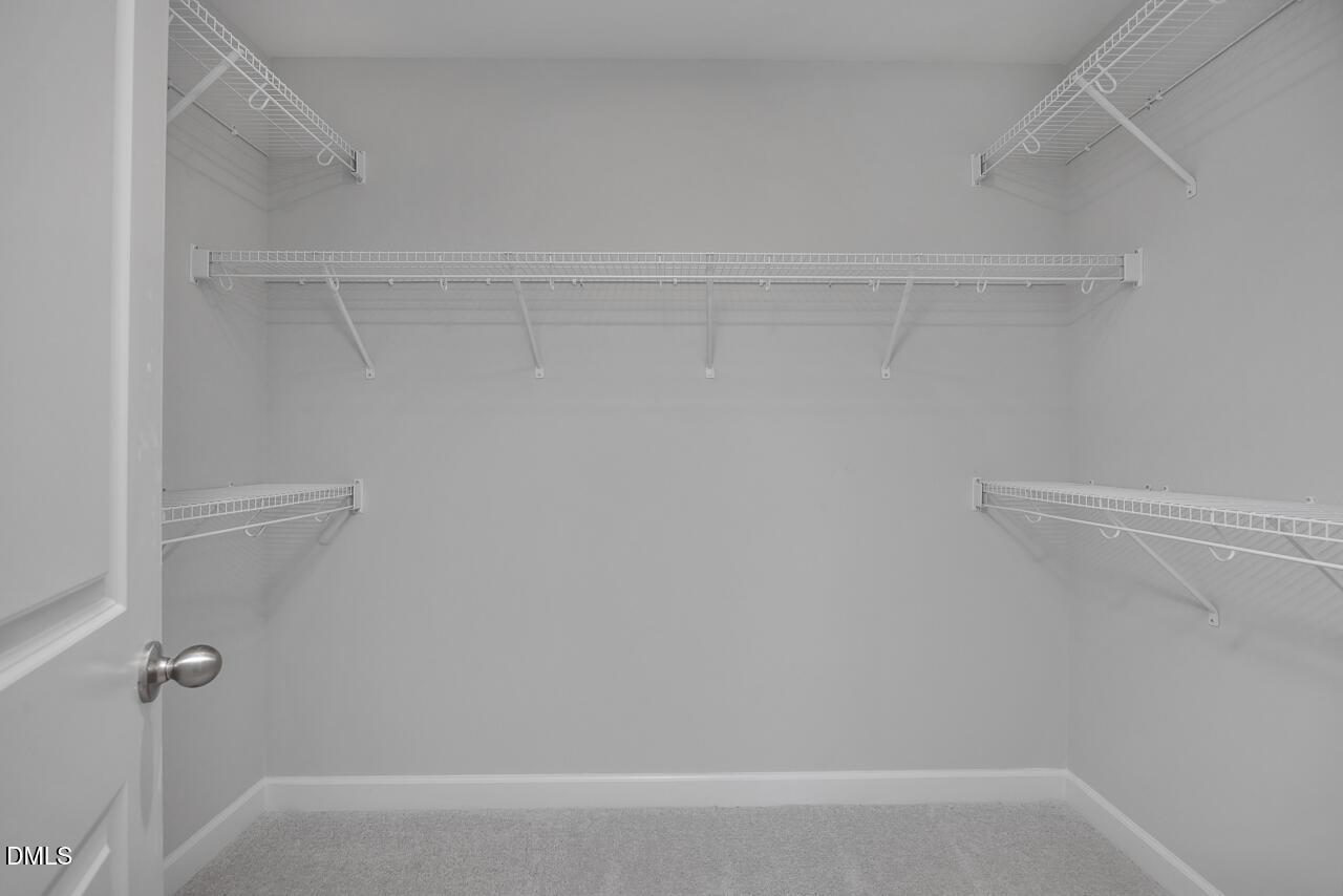 Walk-in closet with white wire shelving in The Adalynn B floor plan at Gregory Village in Lillington, North Carolina.