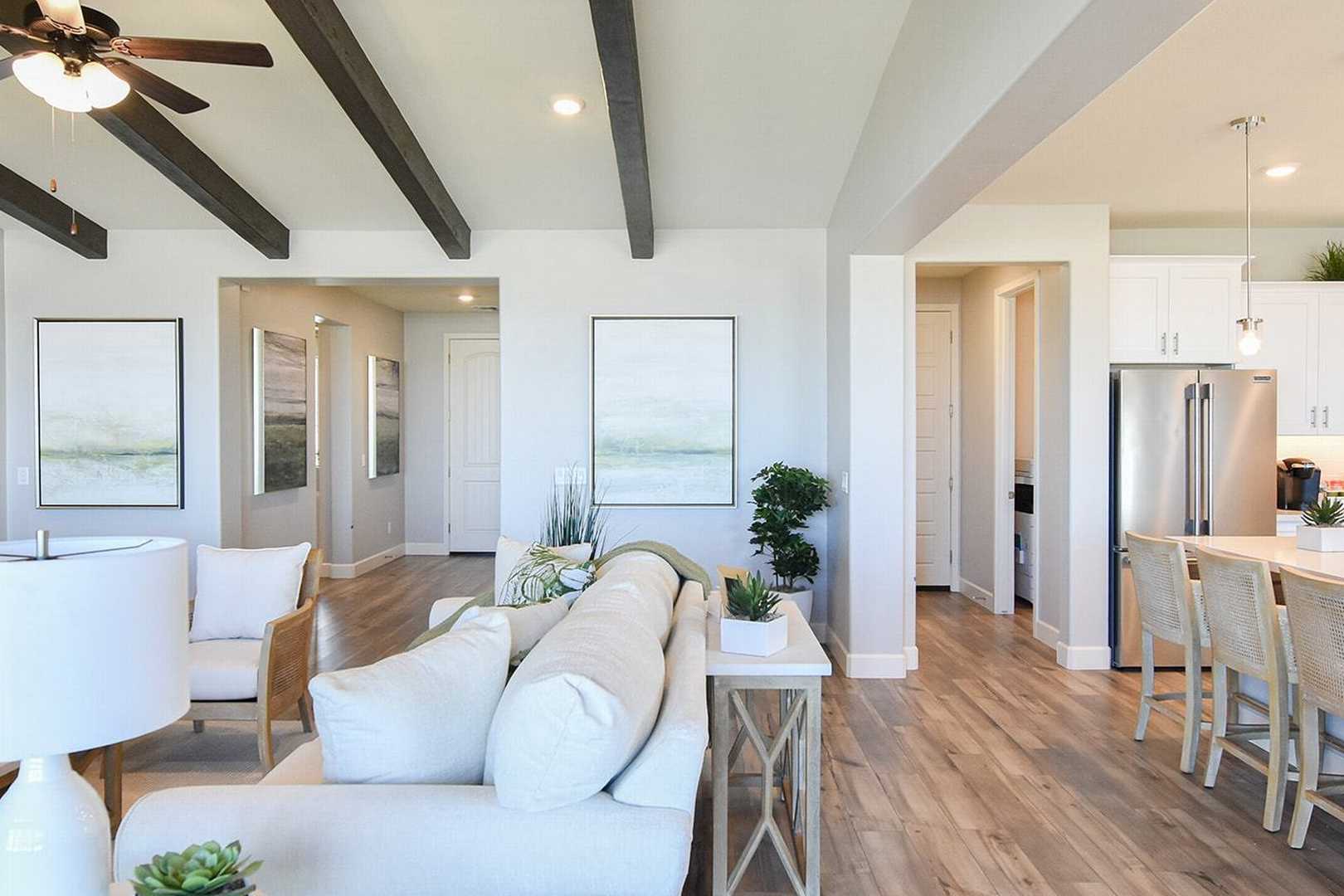Open-concept living and kitchen in The Summit B featuring white sofa, large island, exposed beams, and hardwood floors
