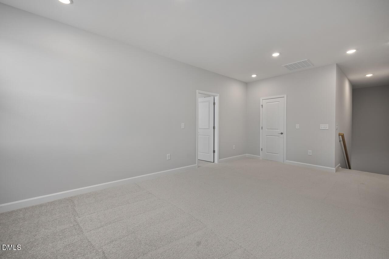 Spacious carpeted loft area in The Ashport L floor plan at Sage on North Main in Wake Forest, North Carolina.