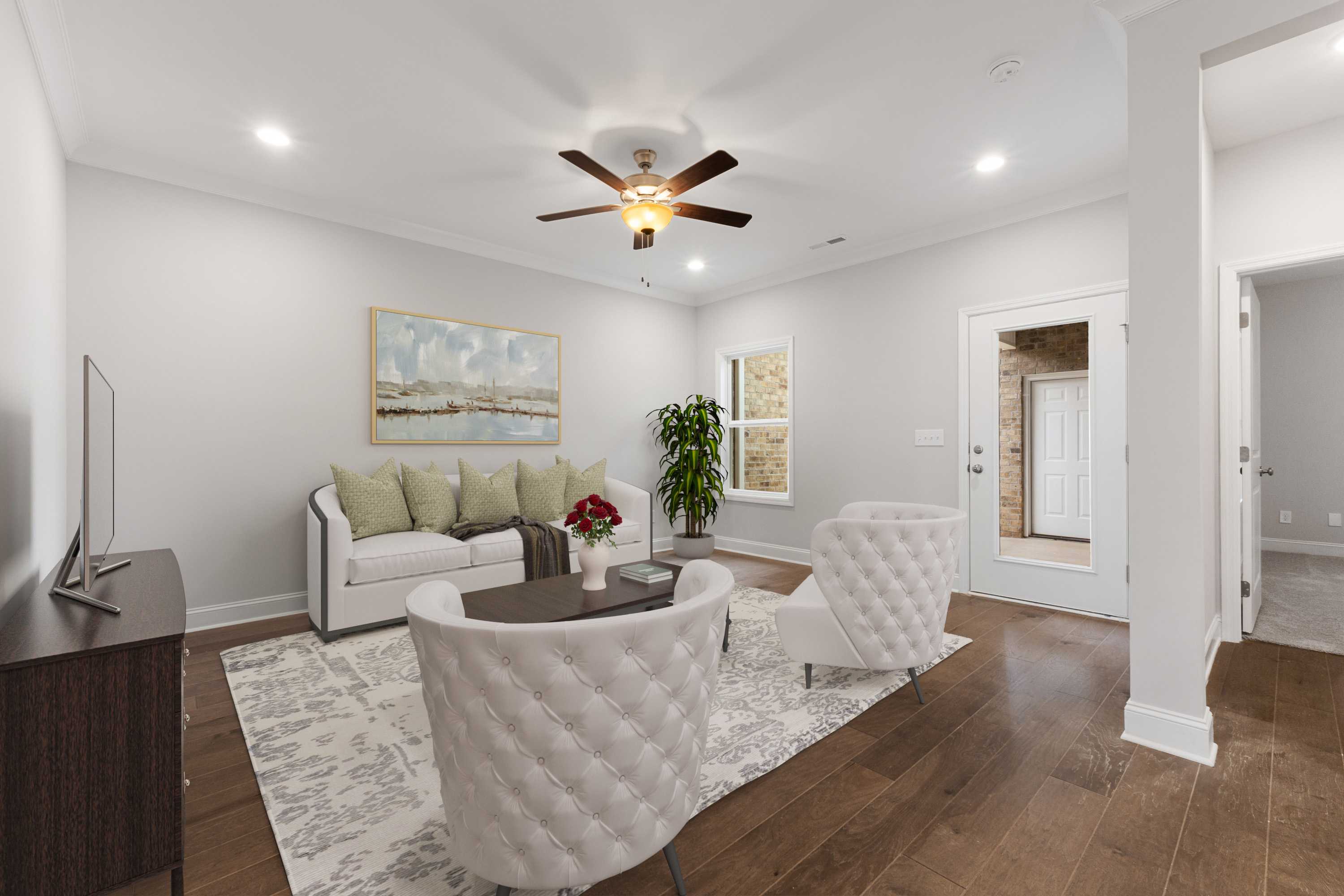 Spacious living room at The Villas at Barnett's Crossing in Madison, Alabama with white sofa, armchairs, hardwood floors, and ceiling fan