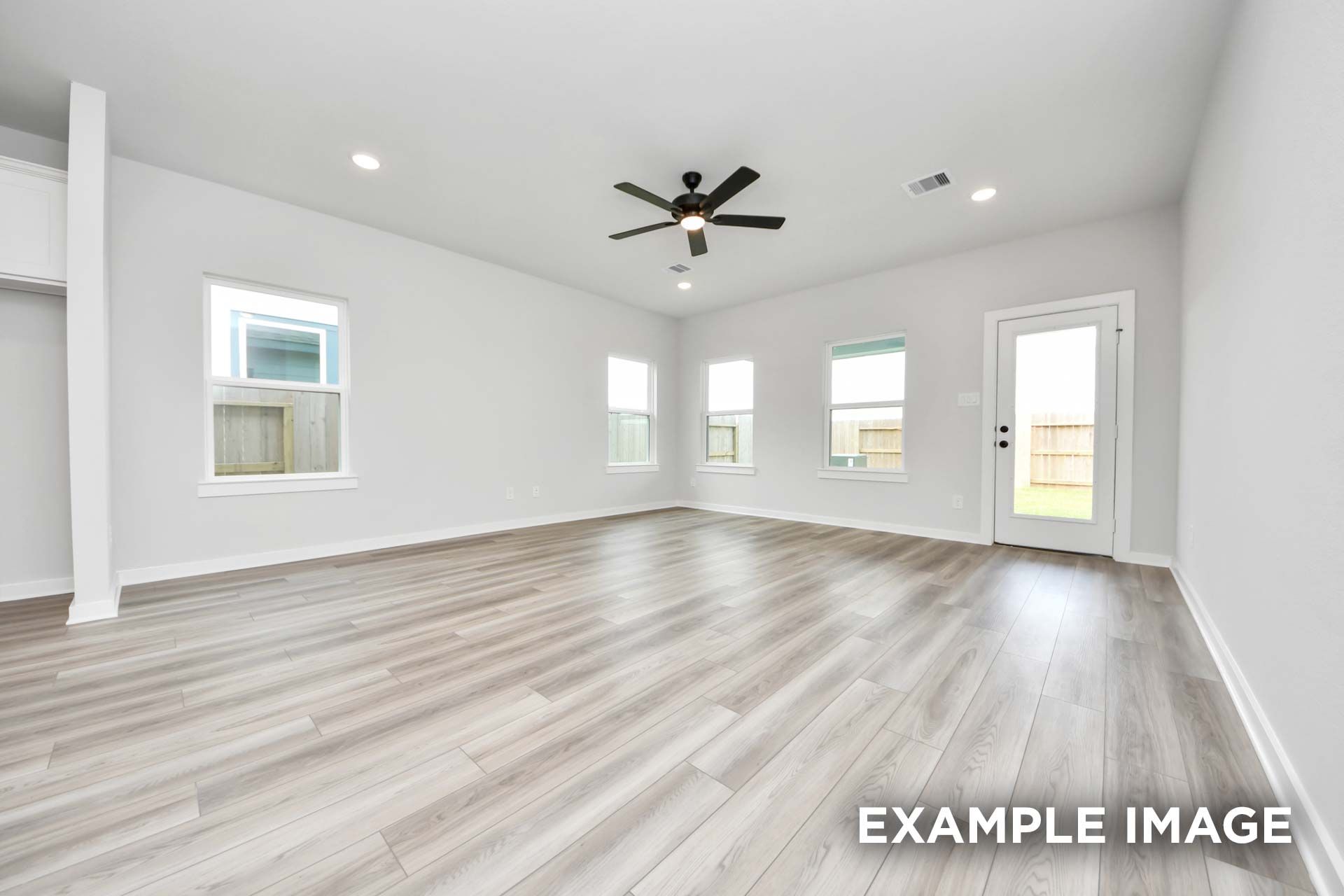 Bright, open-concept living area in The Sorrento featuring modern wood-look flooring, recessed lighting, and backyard access.