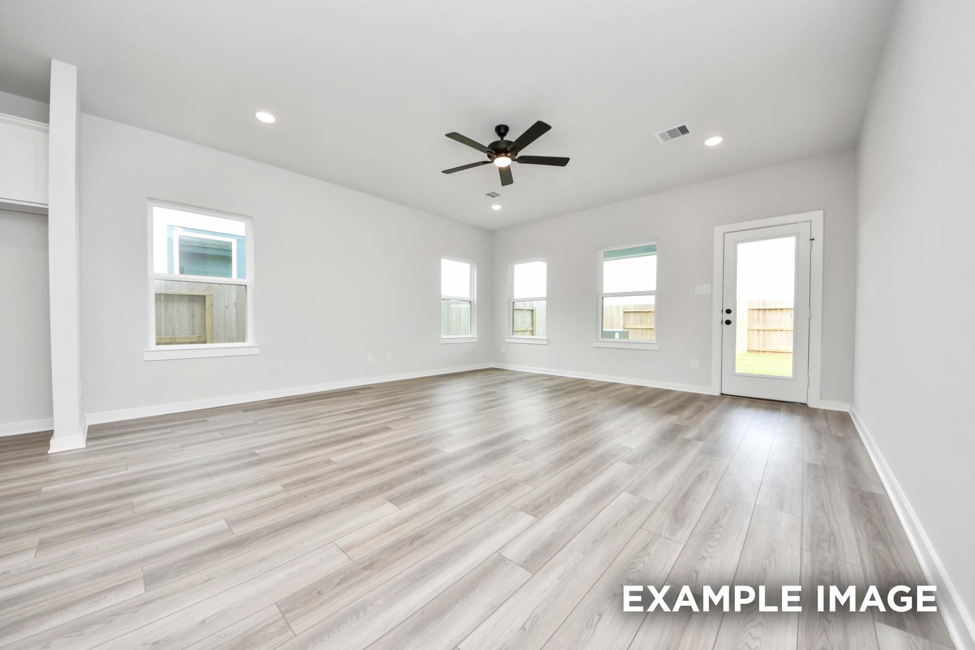 Bright, open-concept living area in The Sorrento featuring modern wood-look flooring, recessed lighting, and backyard access.