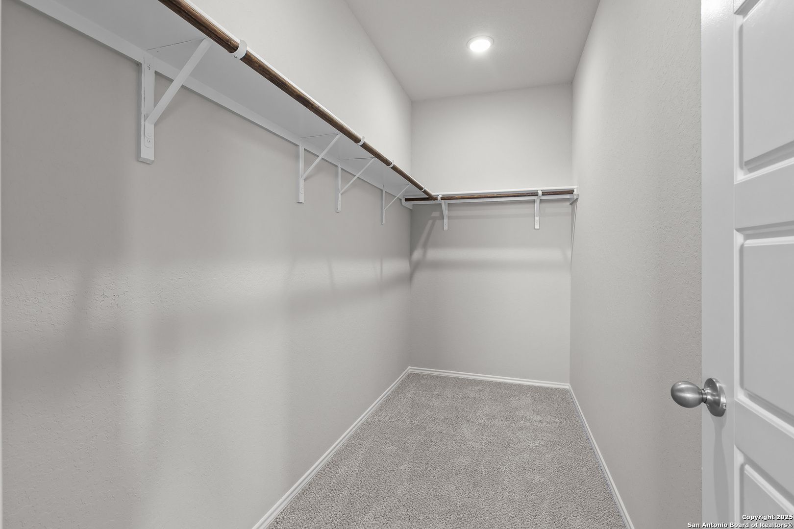 Spacious walk-in closet with built-in wooden shelves, neutral walls, and carpet floor in Davidson Homes The Colorado B, San Antonio