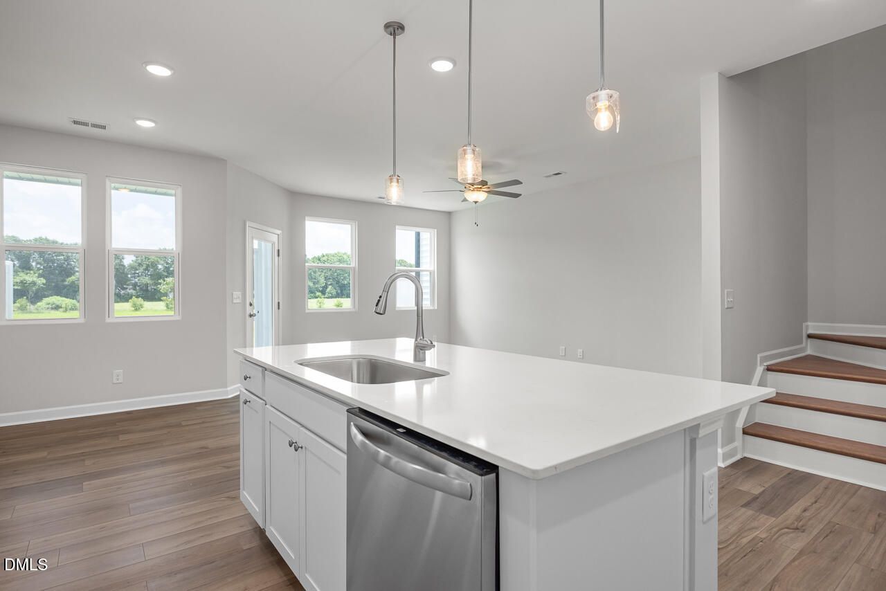 Modern kitchen island with quartz countertops and pendant lighting in The Graham floor plan by Davidson Homes, Fuquay-Varina.