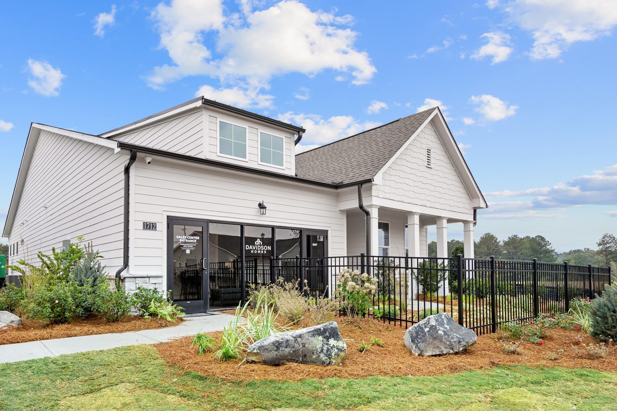 Modern white farmhouse model home at Kelly Preserve in Loganville GA with covered porch, black fence, and landscaped yard