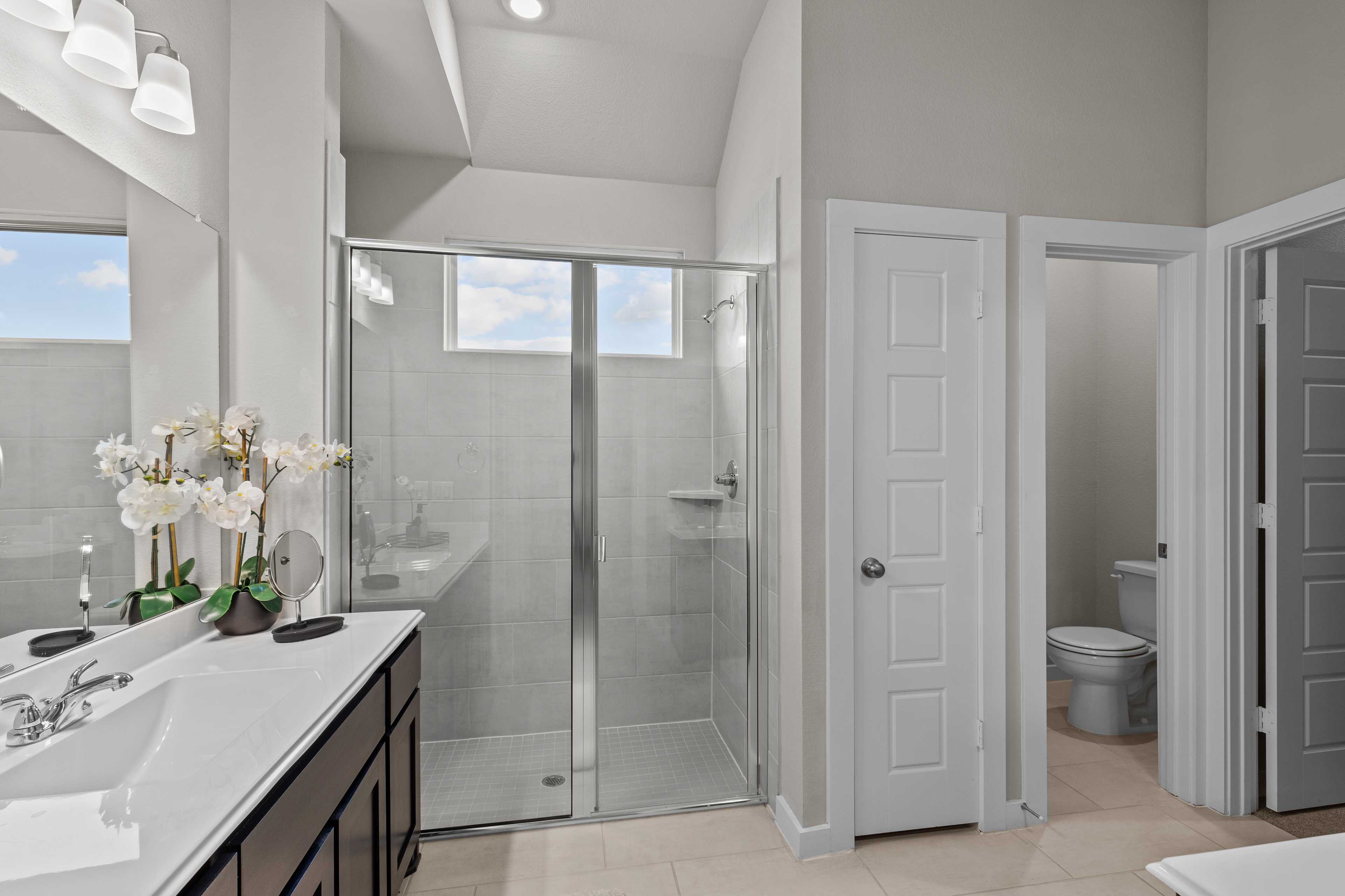 Spacious master bathroom in Hannah Heights Seguin Texas with glass shower, double vanity, and orchids
