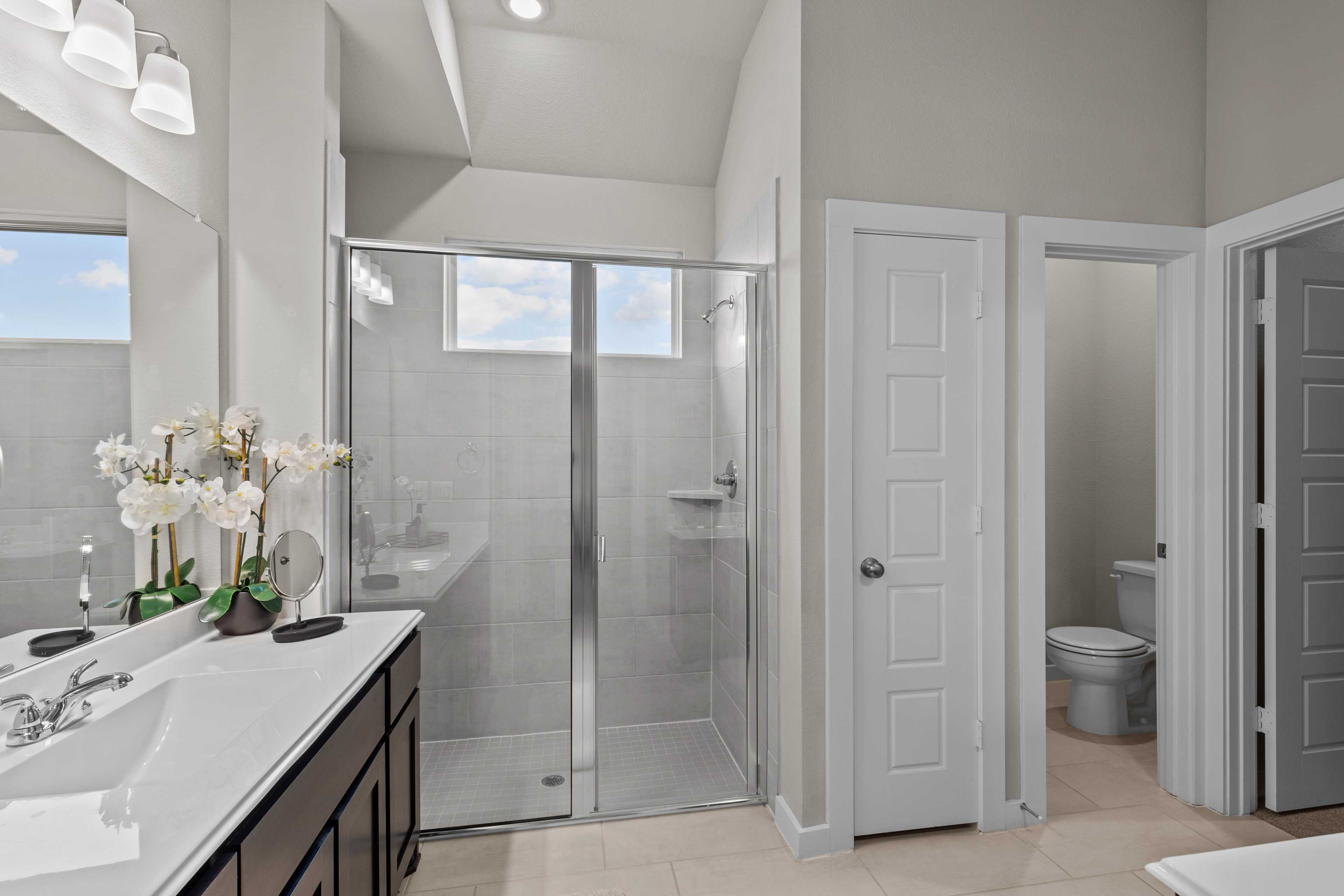 Spacious master bathroom in Hannah Heights Seguin Texas with glass shower, double vanity, and orchids