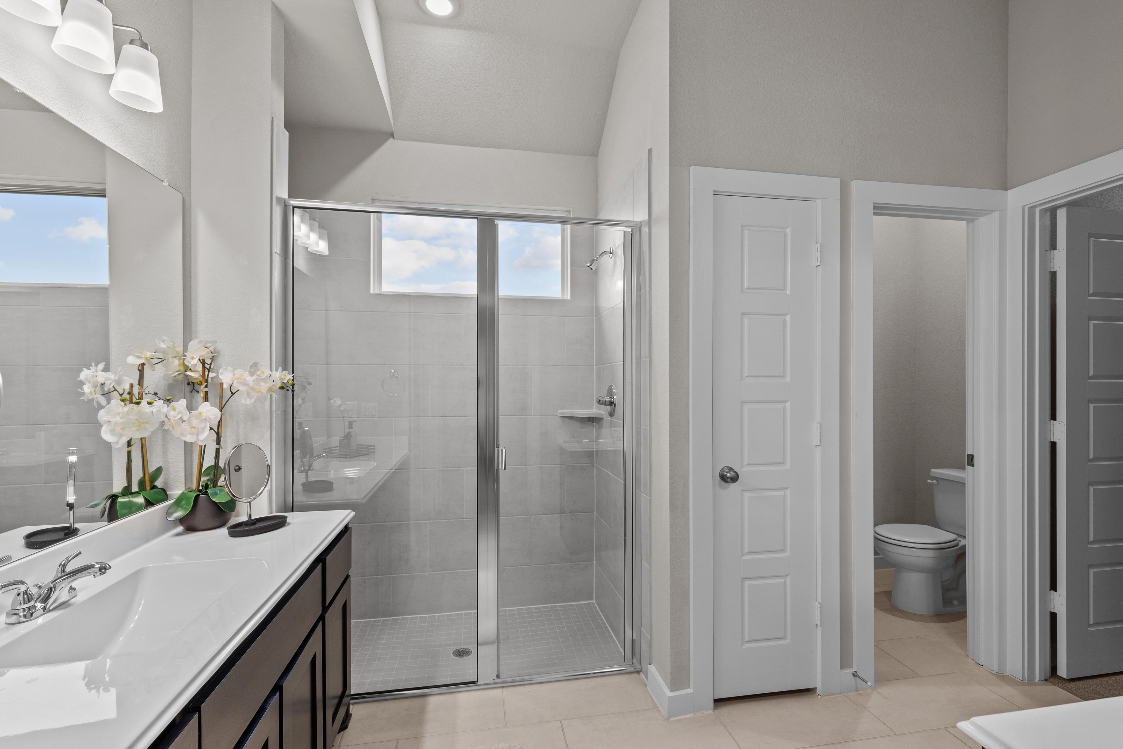 Spacious master bathroom in Hannah Heights Seguin Texas with glass shower, double vanity, and orchids