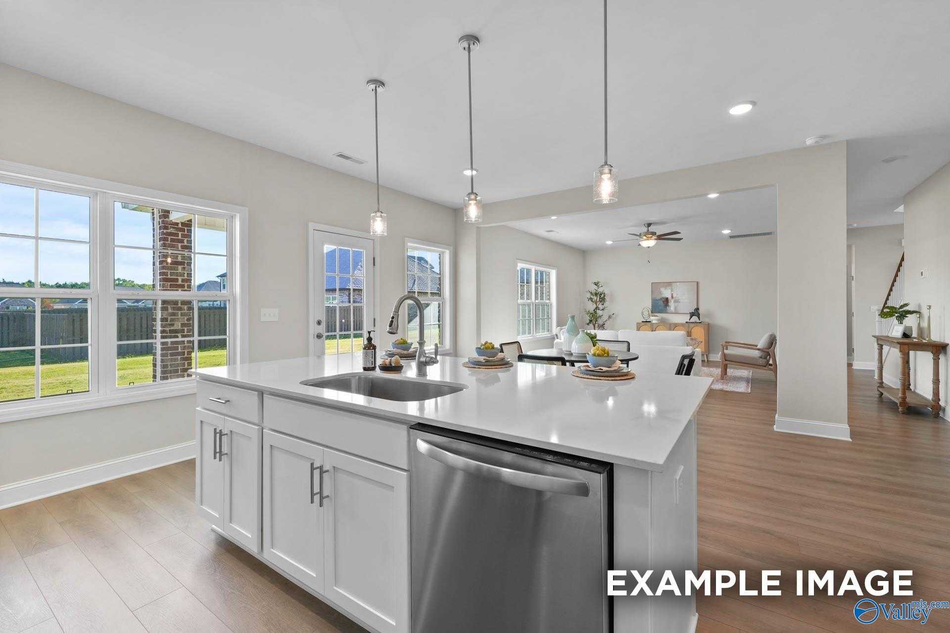 Modern open-concept kitchen with white island sink, stainless dishwasher, and backyard view in Davidson Homes The Madison A, Harvest, AL