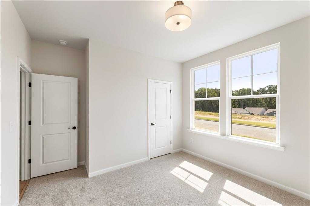 Bright secondary bedroom with large windows and wooded view in Davidson Homes The Daphne C, Kelly Preserve, Loganville
