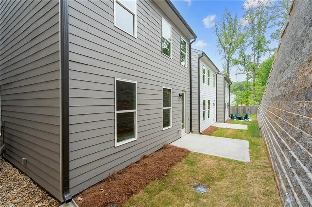 Two-story gray-sided home exterior with large windows, concrete patio, and landscaped yard in The Village at Shallowford, Kennesaw, Georgia