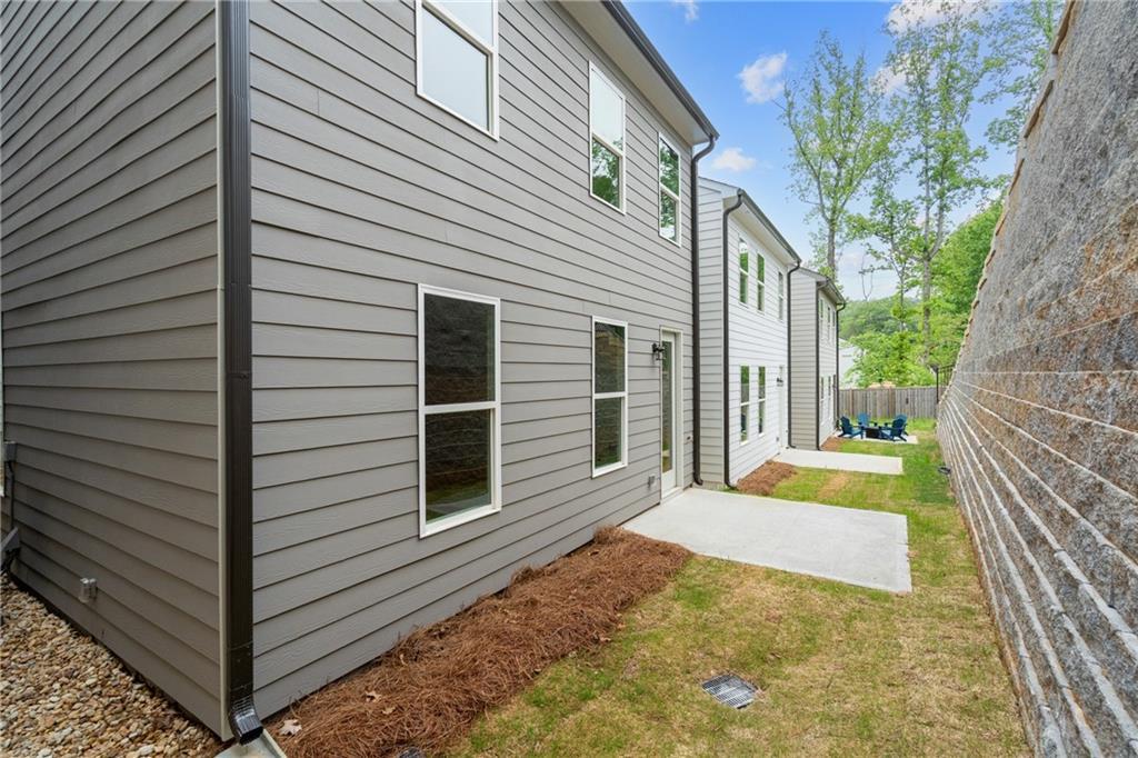 Modern 2-story gray siding home with windows, side patio, fenced backyard, and trees in The Village at Shallowford, Kennesaw, Georgia