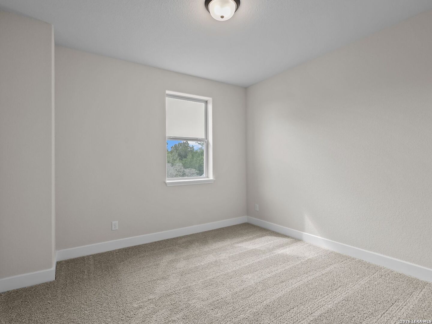 Bright secondary bedroom with neutral carpet and window view in The Belmont H floor plan at Potranco Oaks, Castroville.