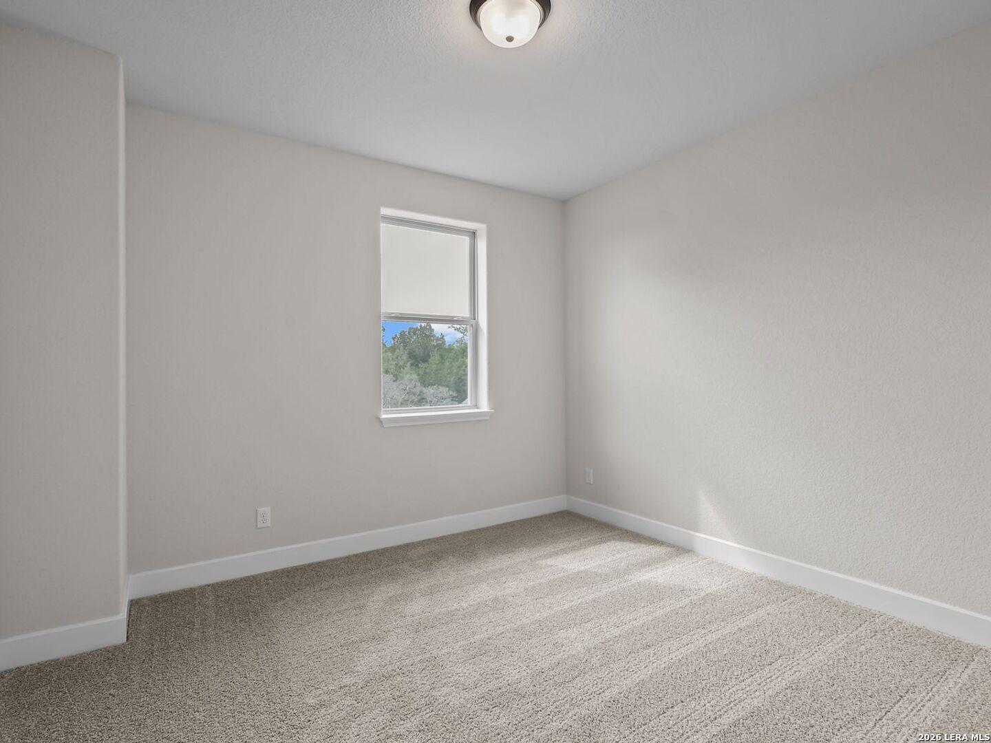 Bright secondary bedroom with neutral carpet and window view in The Belmont H floor plan at Potranco Oaks, Castroville.