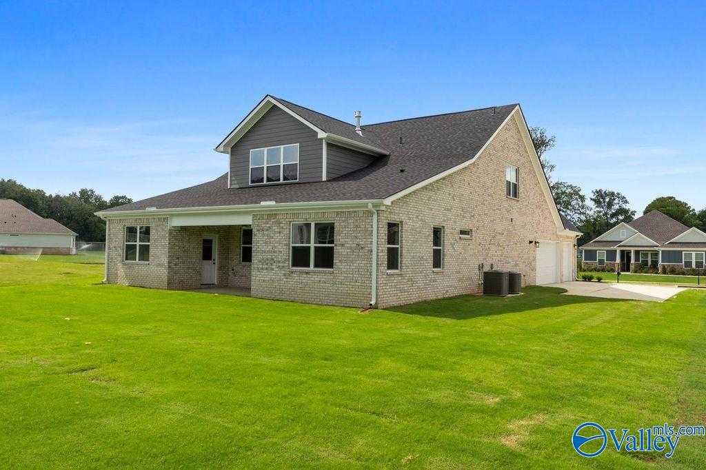 Brick side exterior of 5-bedroom The Oxford home with 2-car garage, covered patio, and lush green yard in The Meadows at Hampton Cove, Owens Cross Roads, Alabama