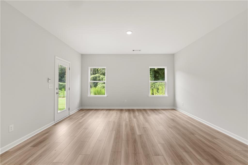 Bright, spacious living area with wood-look flooring and backyard access in The Russell A floor plan at Cedar Farms, Winder.