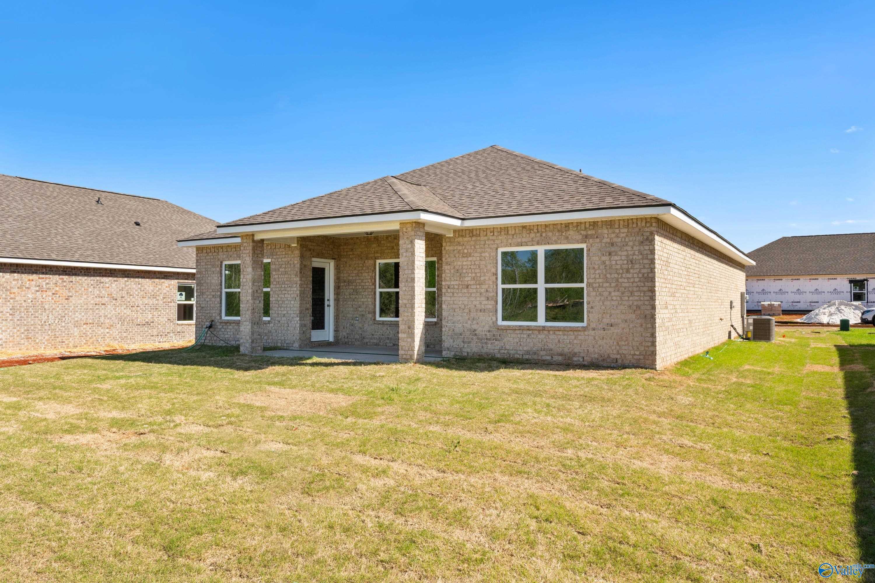 Single-story brick home with covered front porch, large windows, and green yard in The Meadows, Athens, Alabama