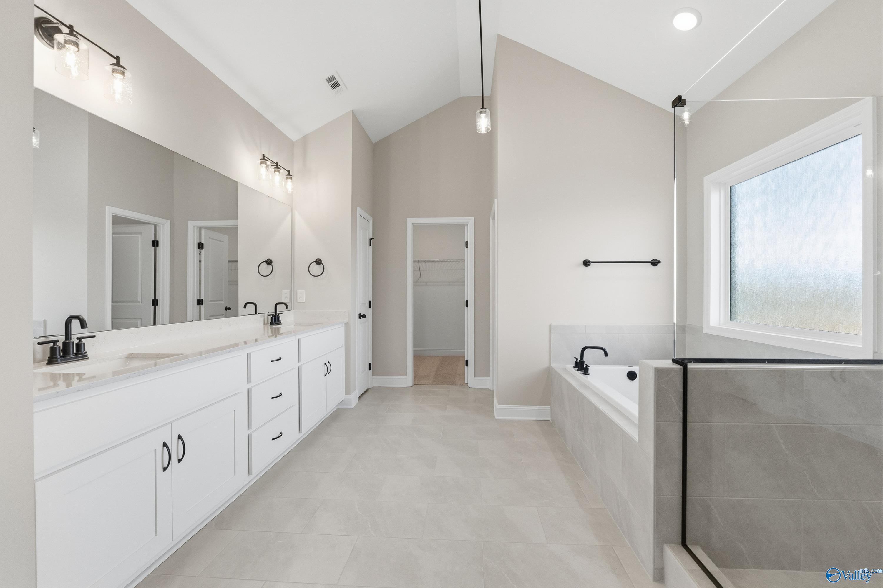 Luxurious master bathroom with double vanity, freestanding tub, walk-in shower, and large window in Davidson Homes The Finleigh, Meridianville, Alabama
