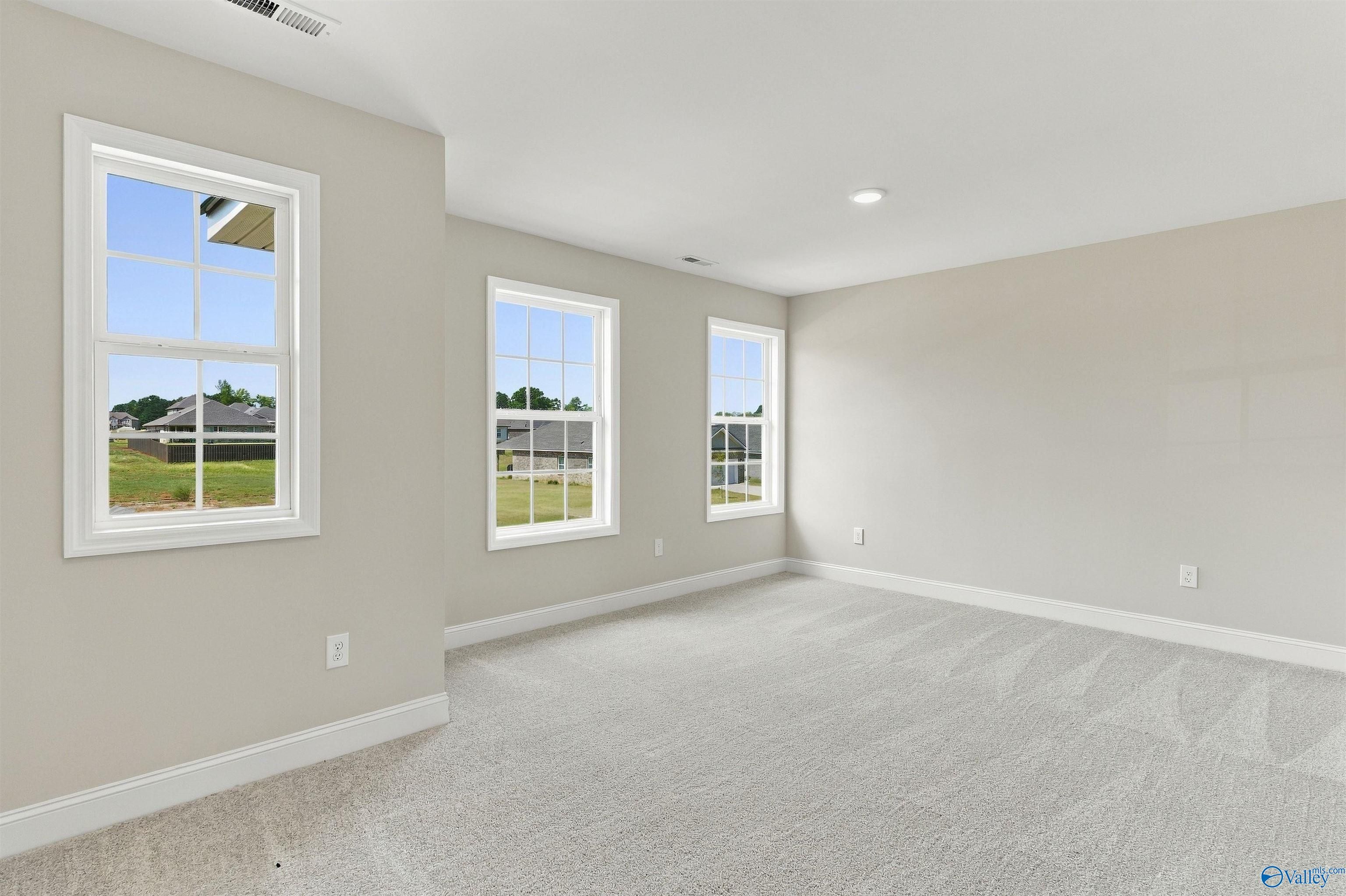 Bright spacious bedroom with carpet and multiple windows overlooking neighborhood in Davidson Homes The Shelby A, Athens, Alabama