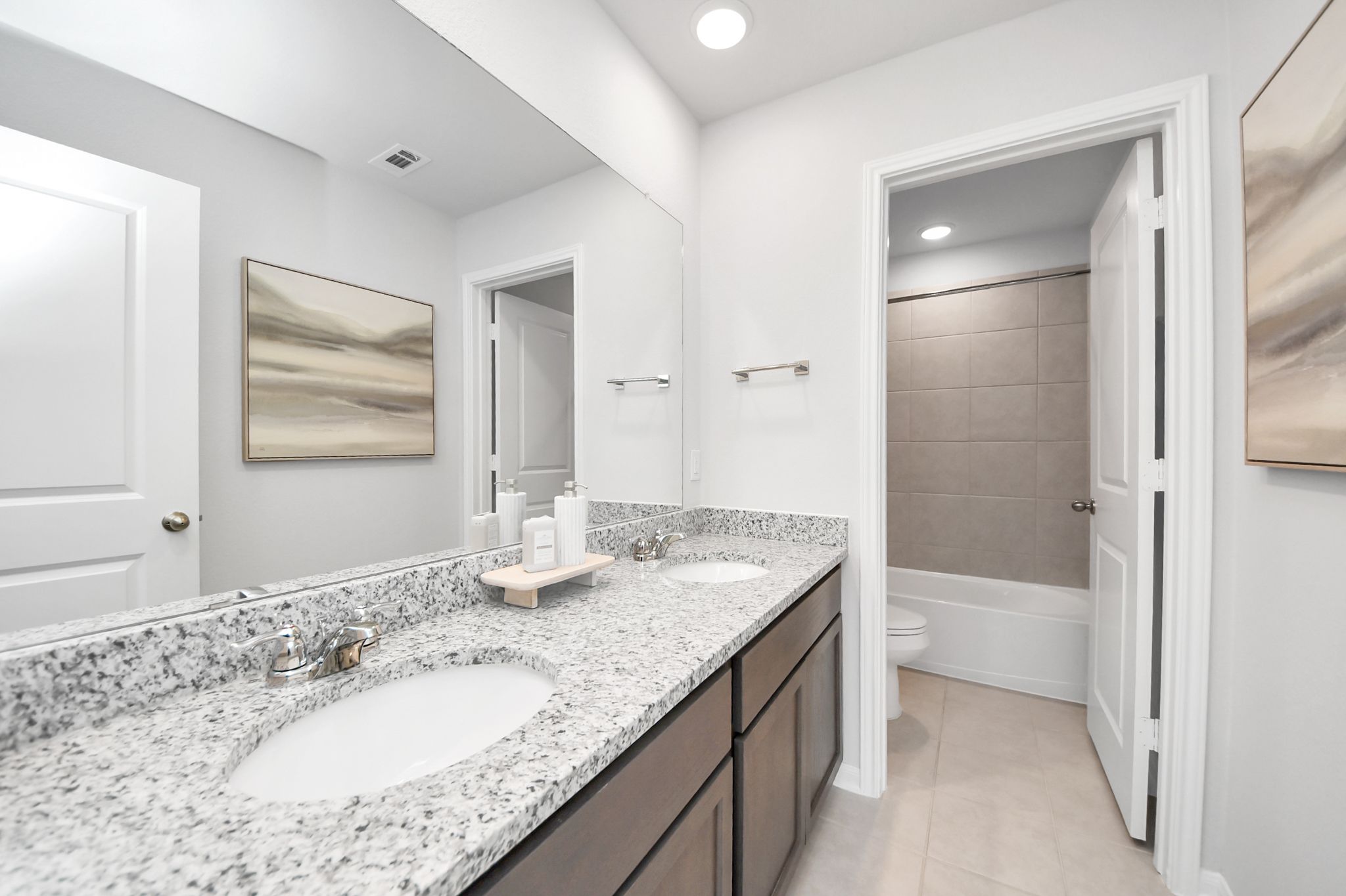 Modern bathroom with double vanity, granite countertops, and tiled shower at Sunterra in Katy, Texas by Davidson Homes.