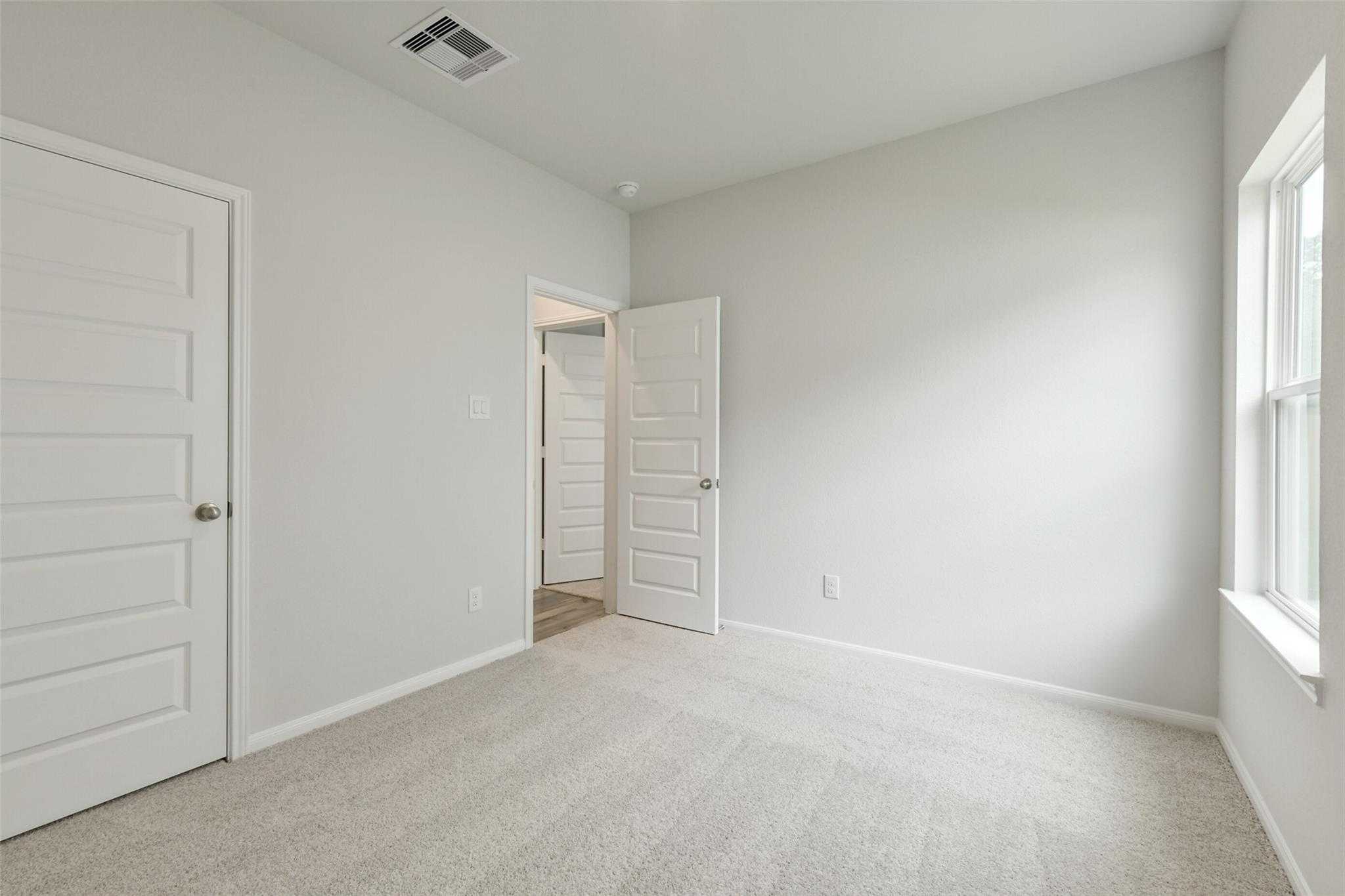 Spacious secondary bedroom with light gray walls, beige carpet, and bathroom access in Davidson Homes The Frio G, Conroe TX