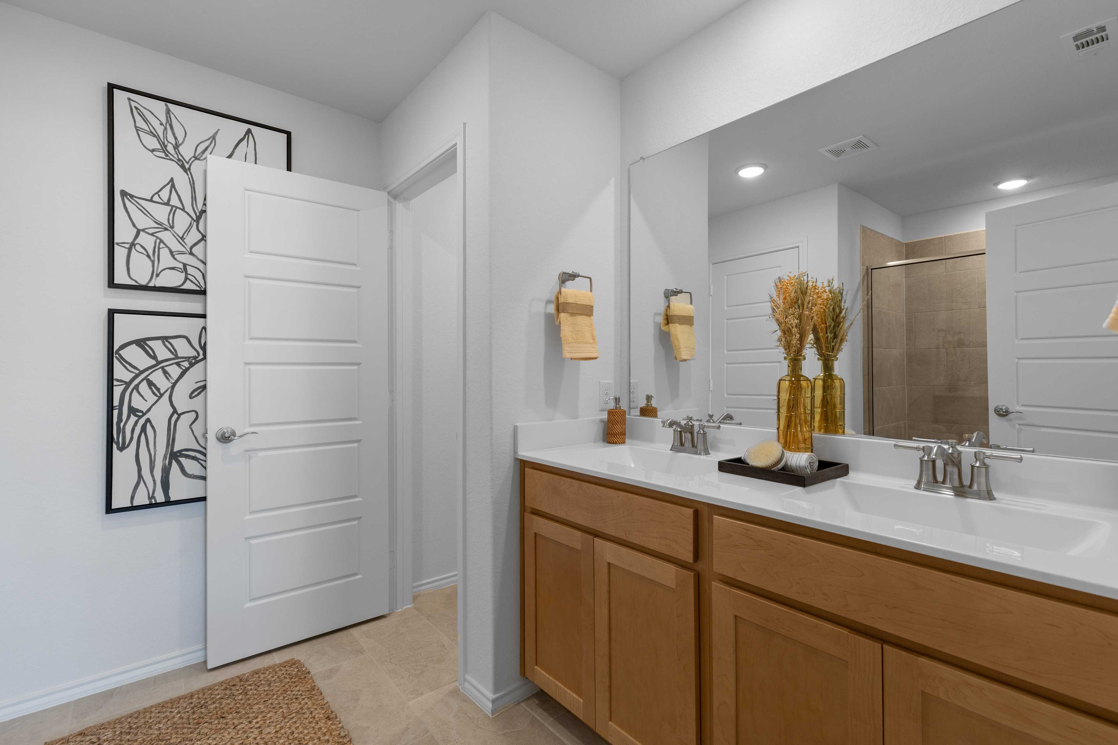 Spacious modern bathroom at Horizon Pointe in Converse Texas with double oak vanity, large mirror, and glass shower