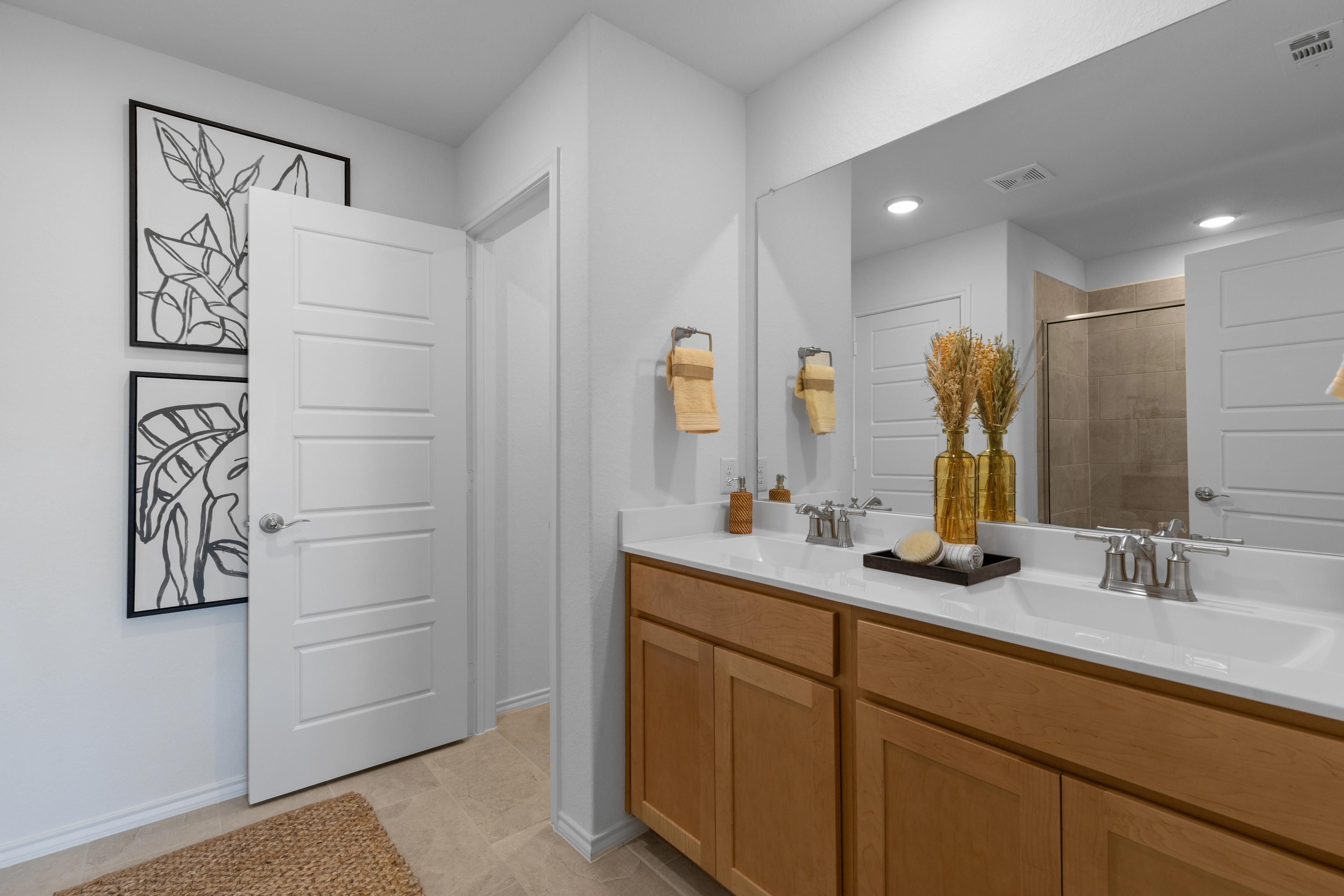 Spacious modern bathroom at Horizon Pointe in Converse Texas with double oak vanity, large mirror, and glass shower