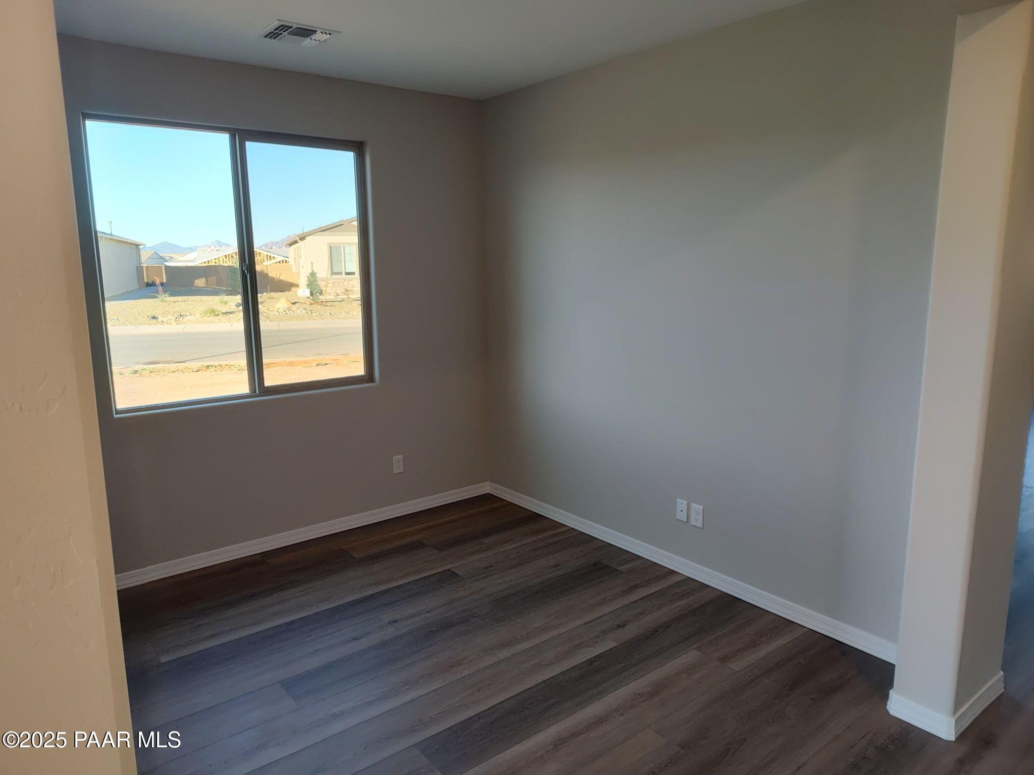 Bright empty bedroom with large window showcasing desert mountains view and hardwood floors in Prescott Valley AZ home