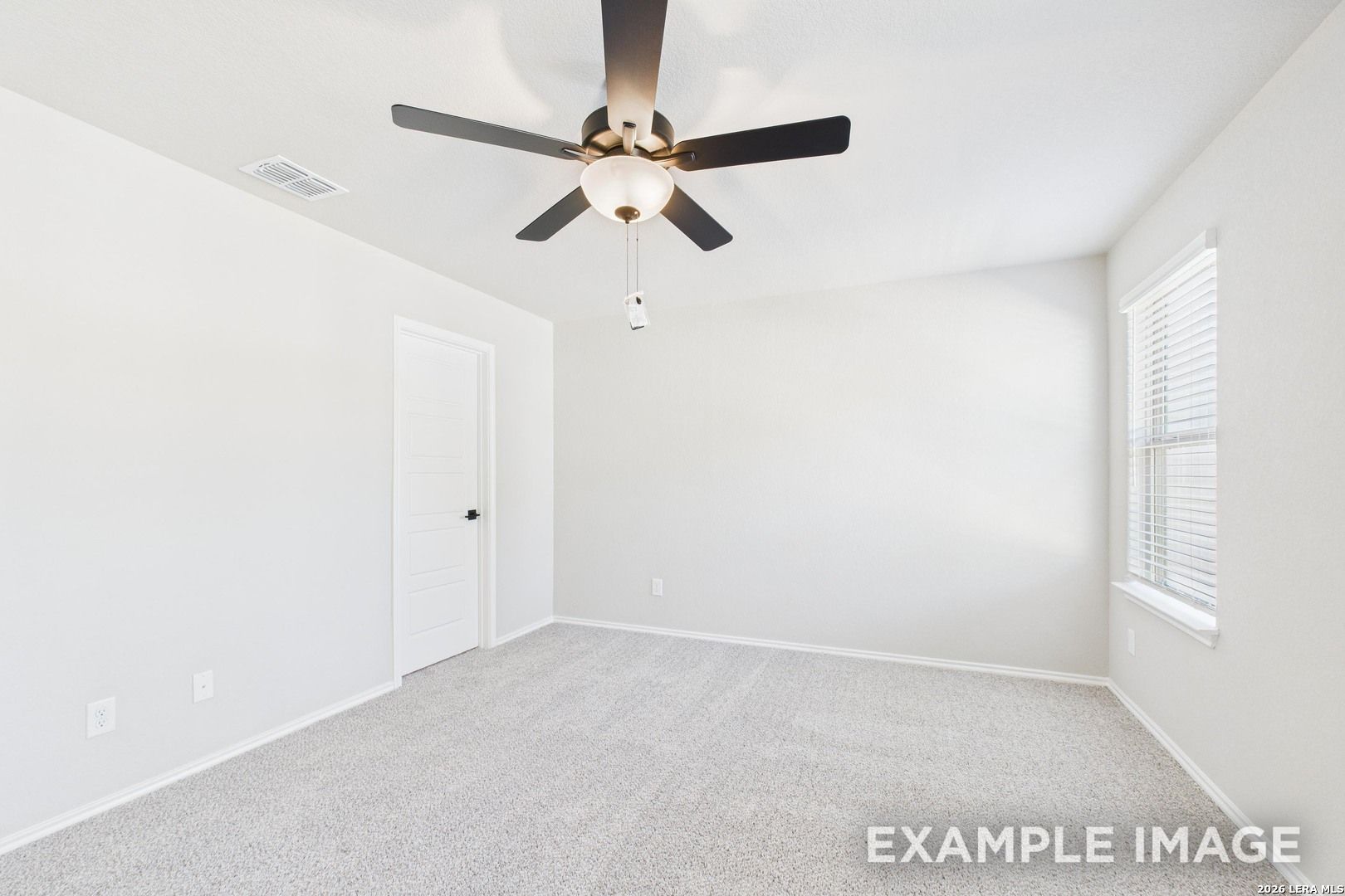 Bright, carpeted bedroom with ceiling fan in The Charlotte B floor plan at Cedar Heights, San Antonio, Texas.