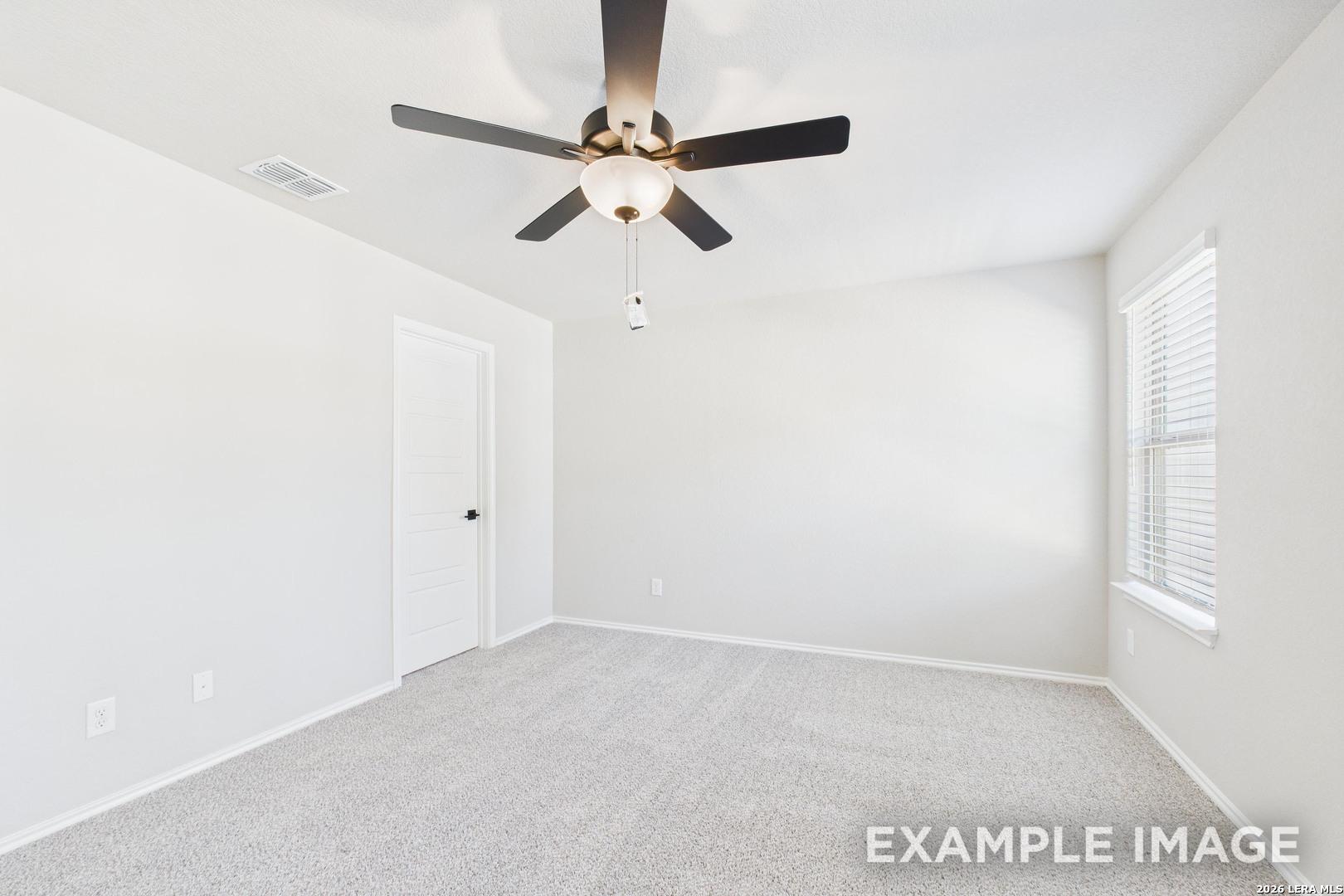 Bright, carpeted bedroom with ceiling fan in The Charlotte B floor plan at Cedar Heights, San Antonio, Texas.