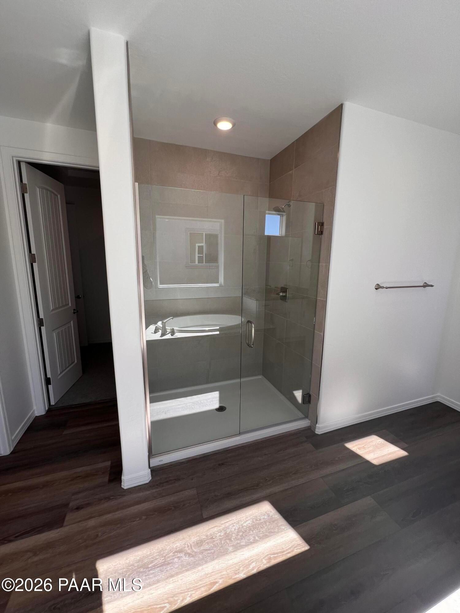 Modern frameless glass shower with beige tile walls and luxury vinyl plank floors in master bath, The Sunrise II A, Prescott, AZ
