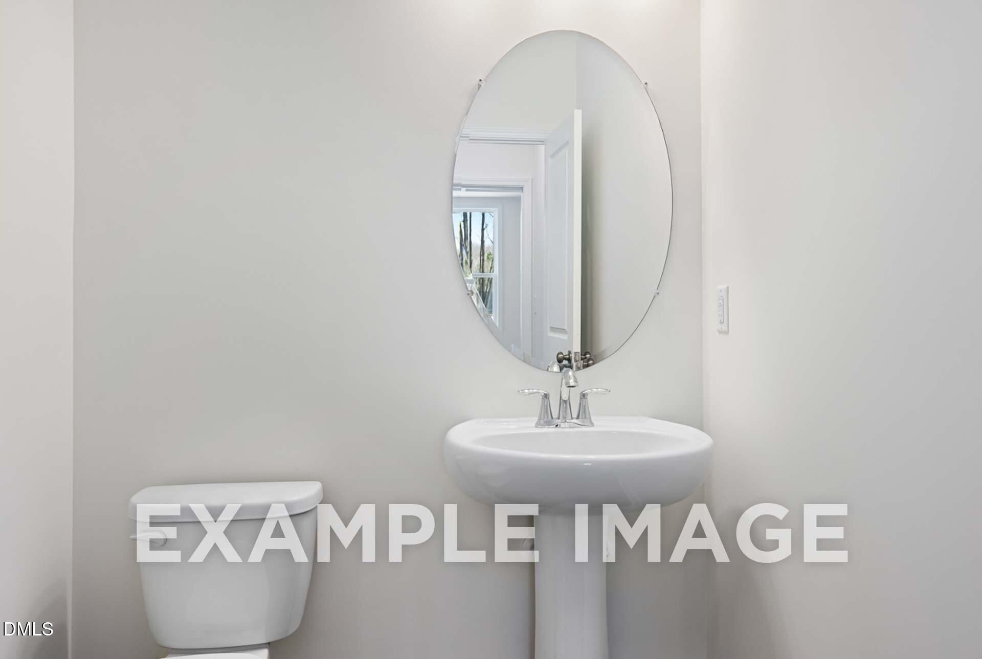 Elegant half bath with white pedestal sink, oval mirror, and neutral walls in Davidson Homes The Ash B, Zebulon, NC