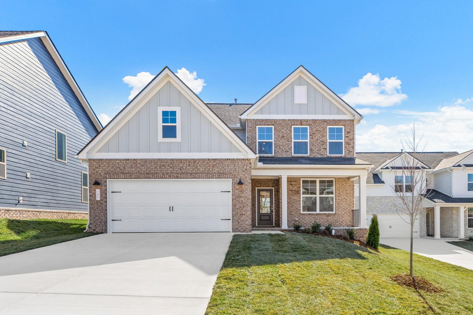 Modern two-story brick home with 2-car garage, front porch, and lush lawn in Woods Crossing, Gallatin, Tennessee by Davidson Homes The Ash A